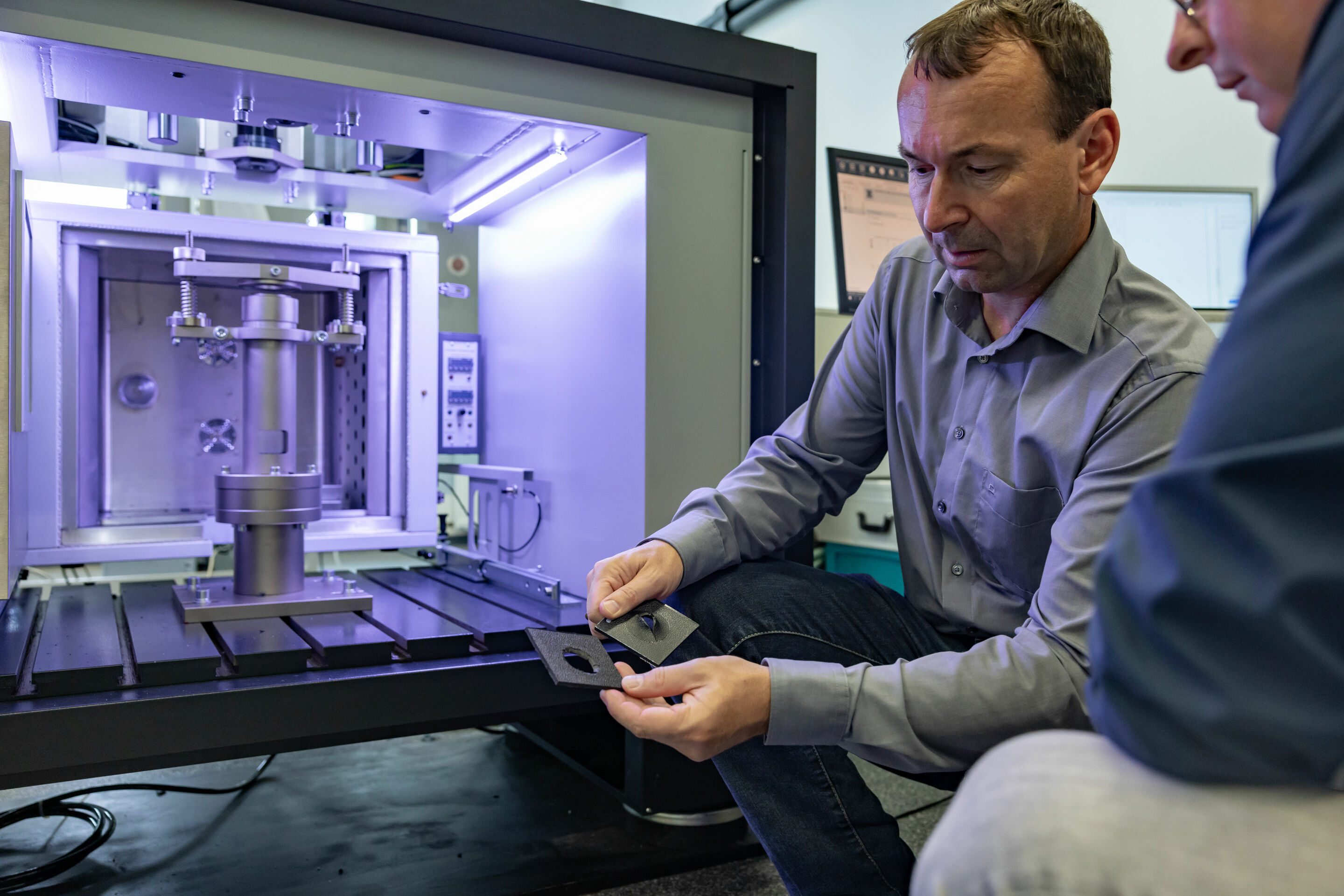 Pilot Project: Physical Recycling Makes Mixed Plastic Waste Recyclable - Quality assurance: employees from Materials Engineering examine plastic samples after a puncture impact test. In this test, the material is subjected to impact stress.
