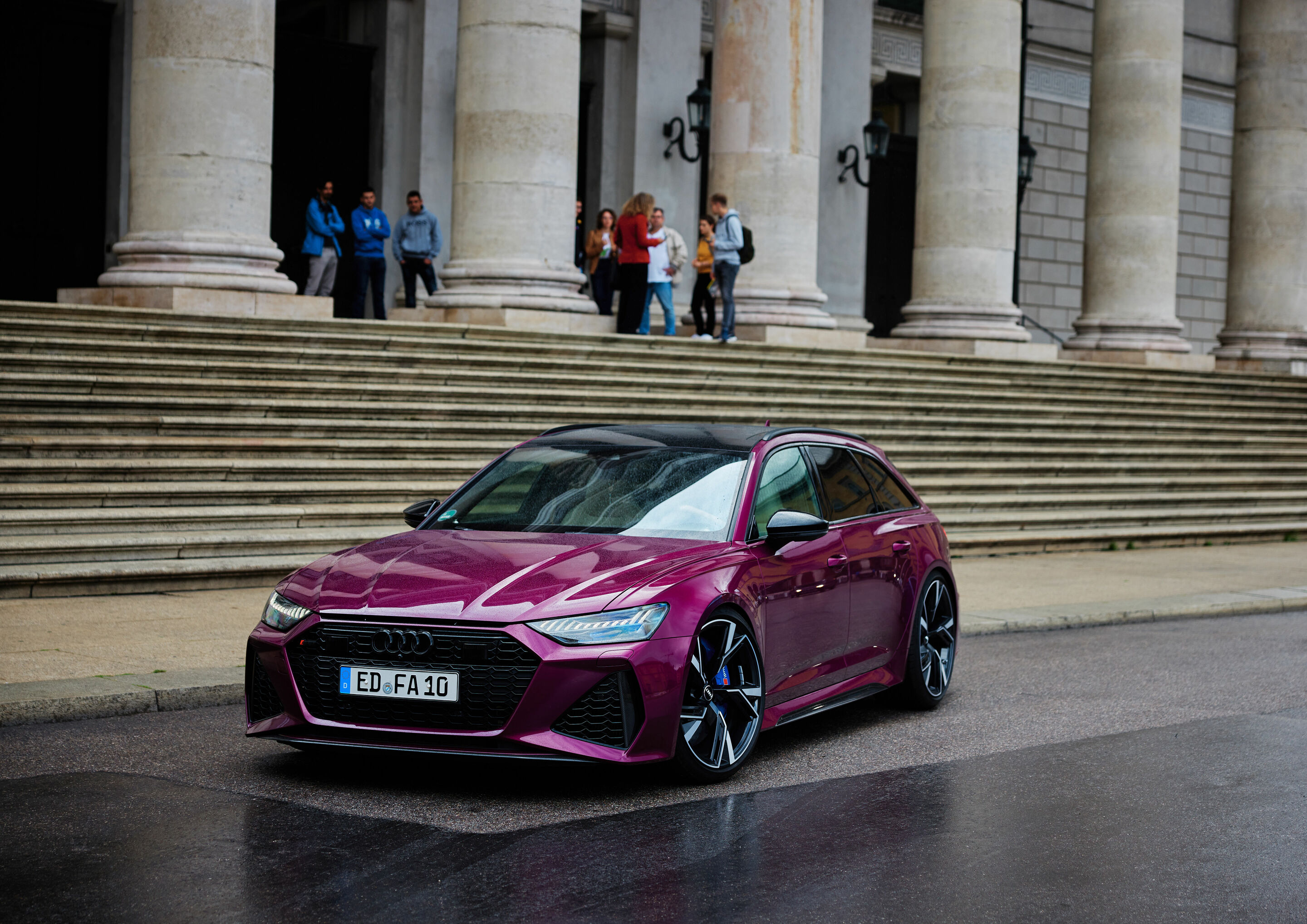 20 years of the Audi RS 6: “All I need is my RS 6!” - An irresistible ride: Three gentlemen at the head of a staircase admire the RS 6 Avant in Berry Pearl Effect.