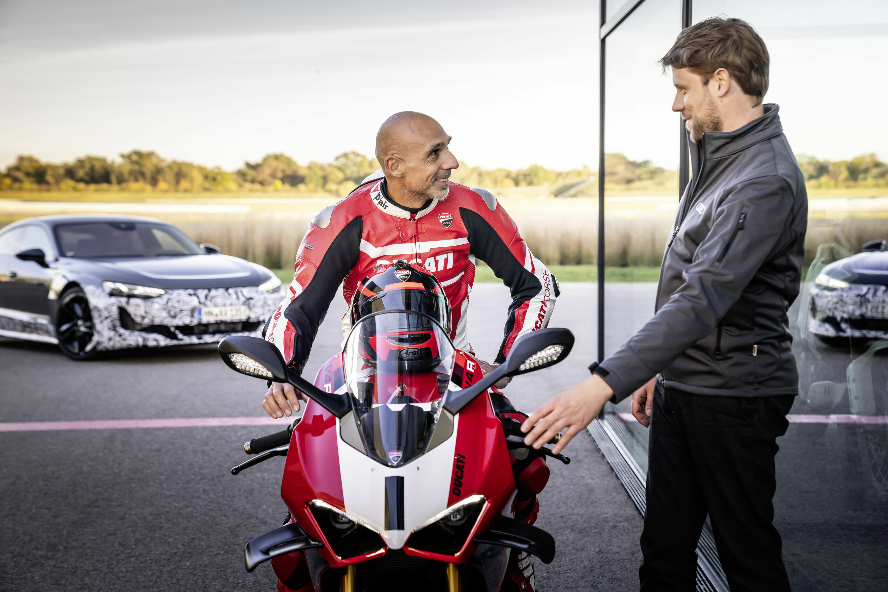 Audi e-tron GT Prototyp - Ducati-Cheftester Alessandro Valia (l.) erklärt Jaan Mattes Reiling die Vorzüge der Ducati Panigale V4 R.