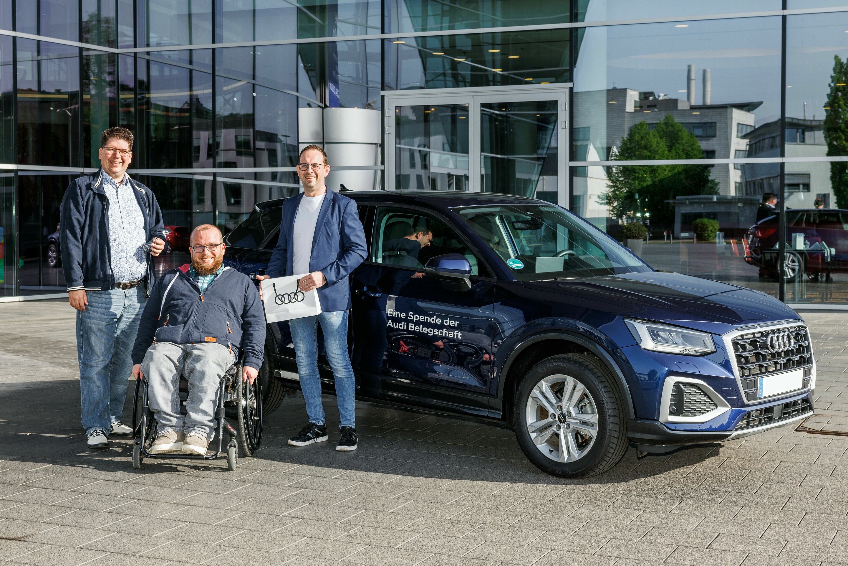 Dank Fahrzeugspende der Audi Belegschaft geht Spielmobil wieder auf Tour - Alexander Reinhart (li.) übergibt den Audi Q2 an den Bundesverband Selbsthilfe Körperbehinderter e. V.