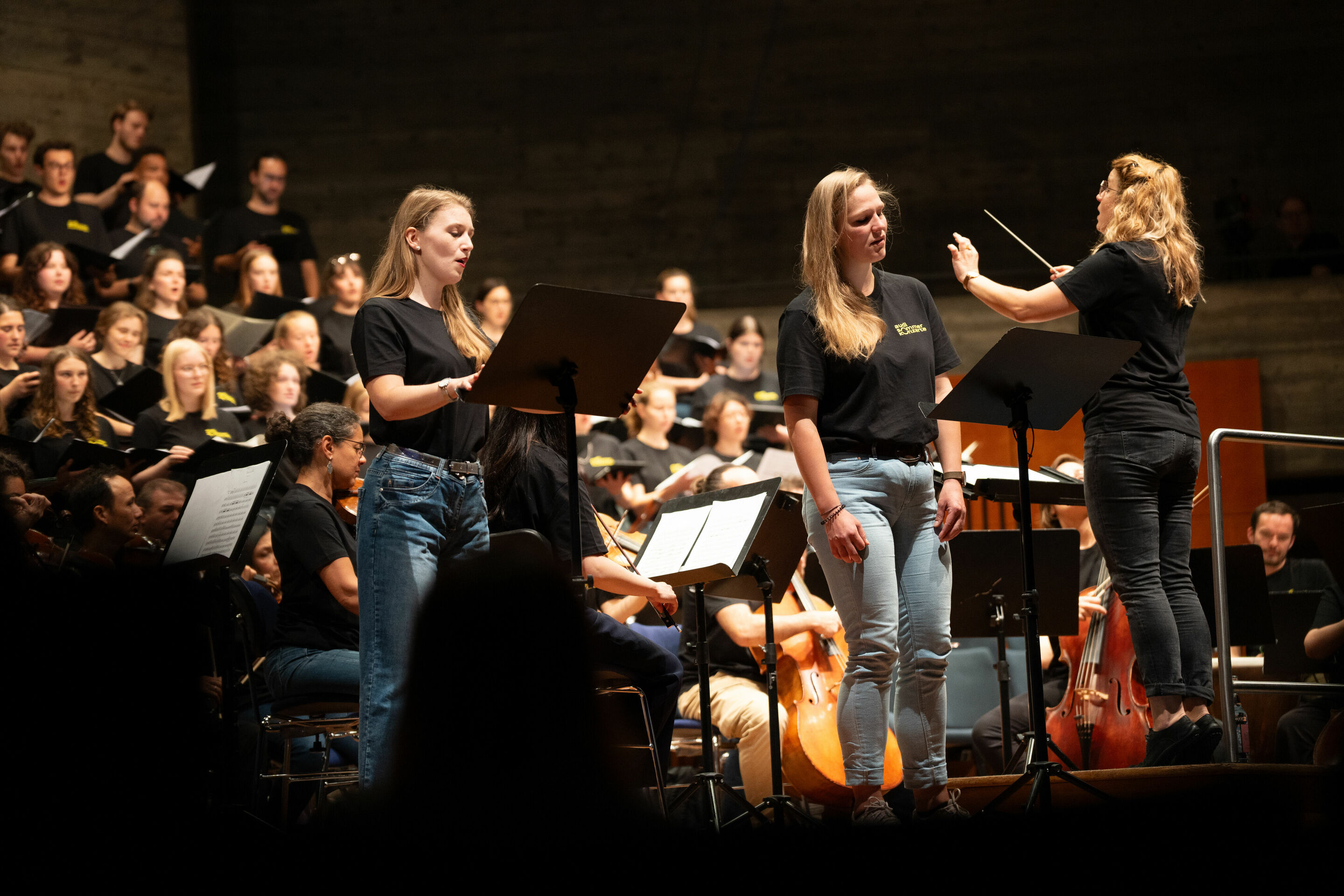 Audi Sommerkonzerte 2024 - Dirigentin Sonja Lachenmayr und die Solistinnen Sandra Bildmann (links) und Paula Rein beim Öffentlichen Workshop: Schüler_innen der Region und die Audi Jugendchorakademie im Festsaal Ingolstadt