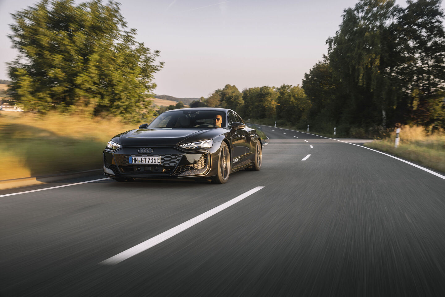 Audi RS e-tron GT performance, A gray Audi RS e-tron GT performance cruises along a country road between fields. The paintwork in Arabica gray metallic reflects the evening sun.