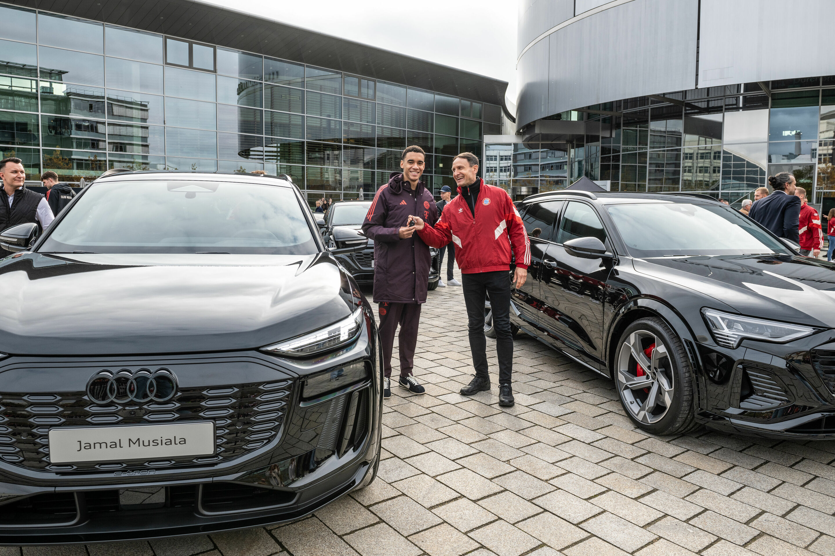 Audi übergibt Dienstwagen an FC Bayern - Fahrzeugübergabe an der Audi Piazza in Ingolstadt: Bayern-Star Jamal Musiala bei der Schlüsselübergabe durch einen Audi Mitarbeiter.