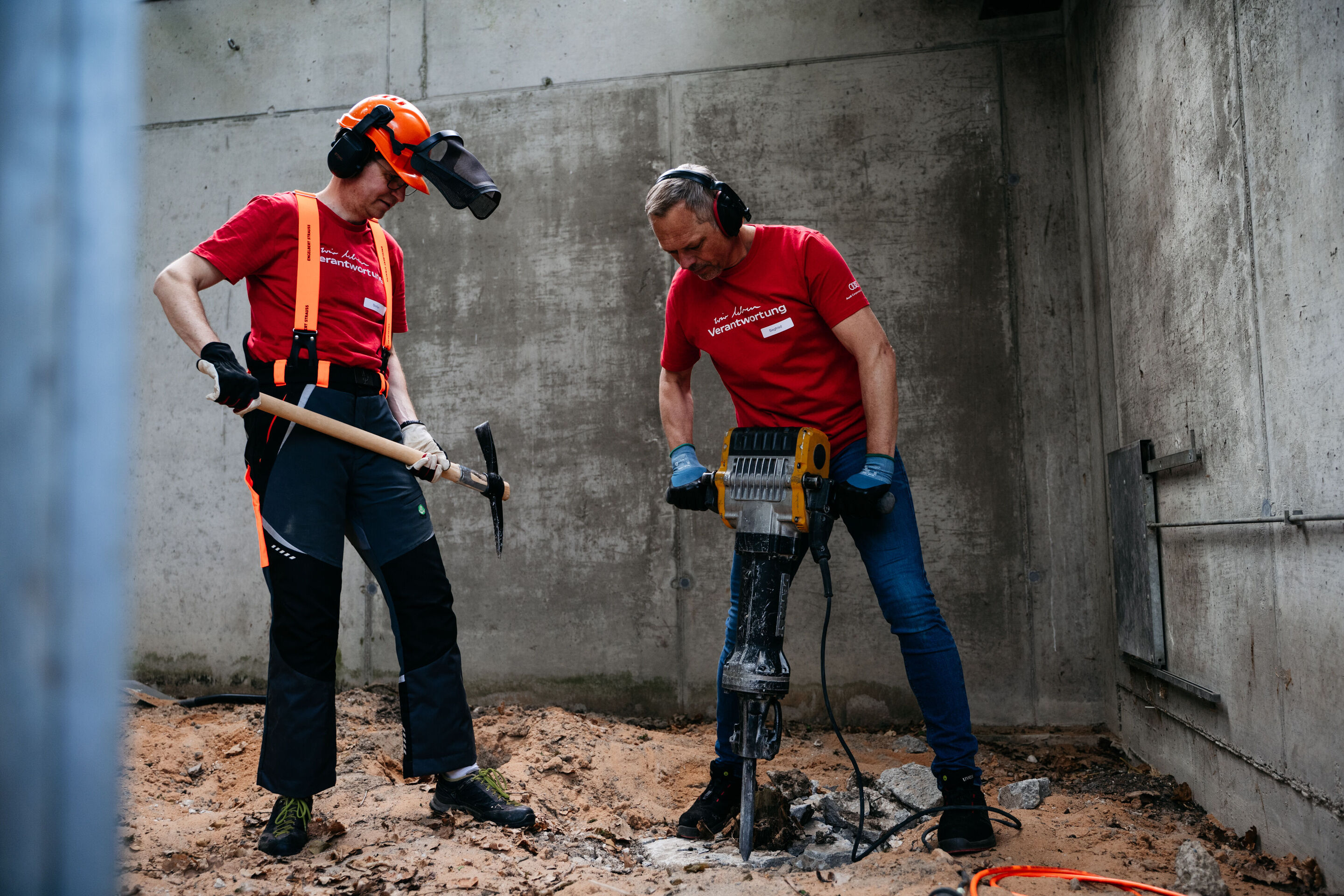 Beschäftigte engagieren sich beim Audi Social Day - Der Ingolstädter Werkleiter Siegfried Schmidtner (r.) bohrt im Ingolstädter Zoo Wasserstern das Fundament für einen Kletterbaum.