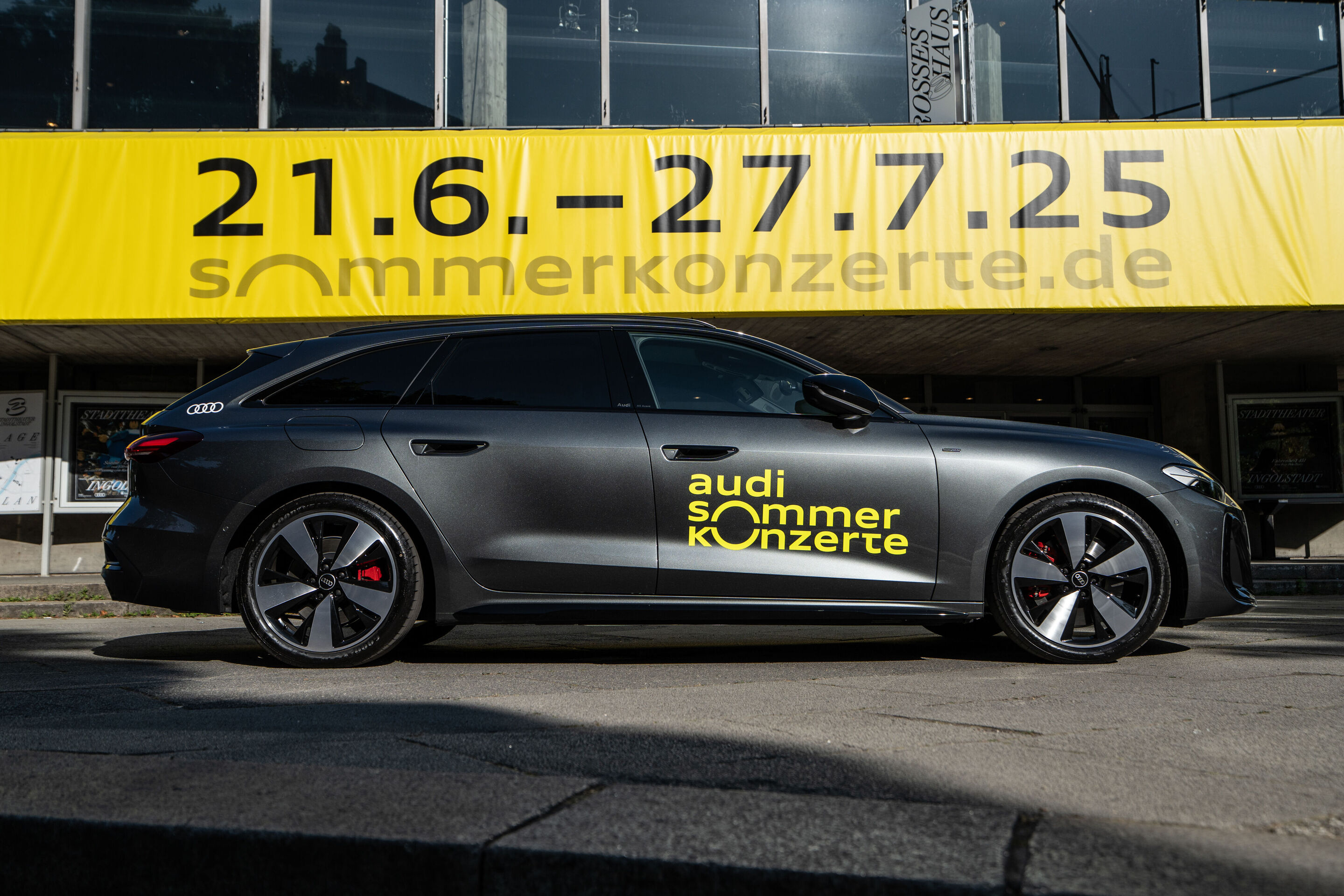 Eröffnungskonzert mit dem Deutschen Symphonie-Orchester Berlin - Der Audi A5 Avant e-hybrid in der Farbe Daytonagrau Perleffekt mit gelben Logo der Audi Sommerkonzerte steht vor dem Stadttheater Ingolstadt. Auf einem großen gelben Plakat, das über dem...