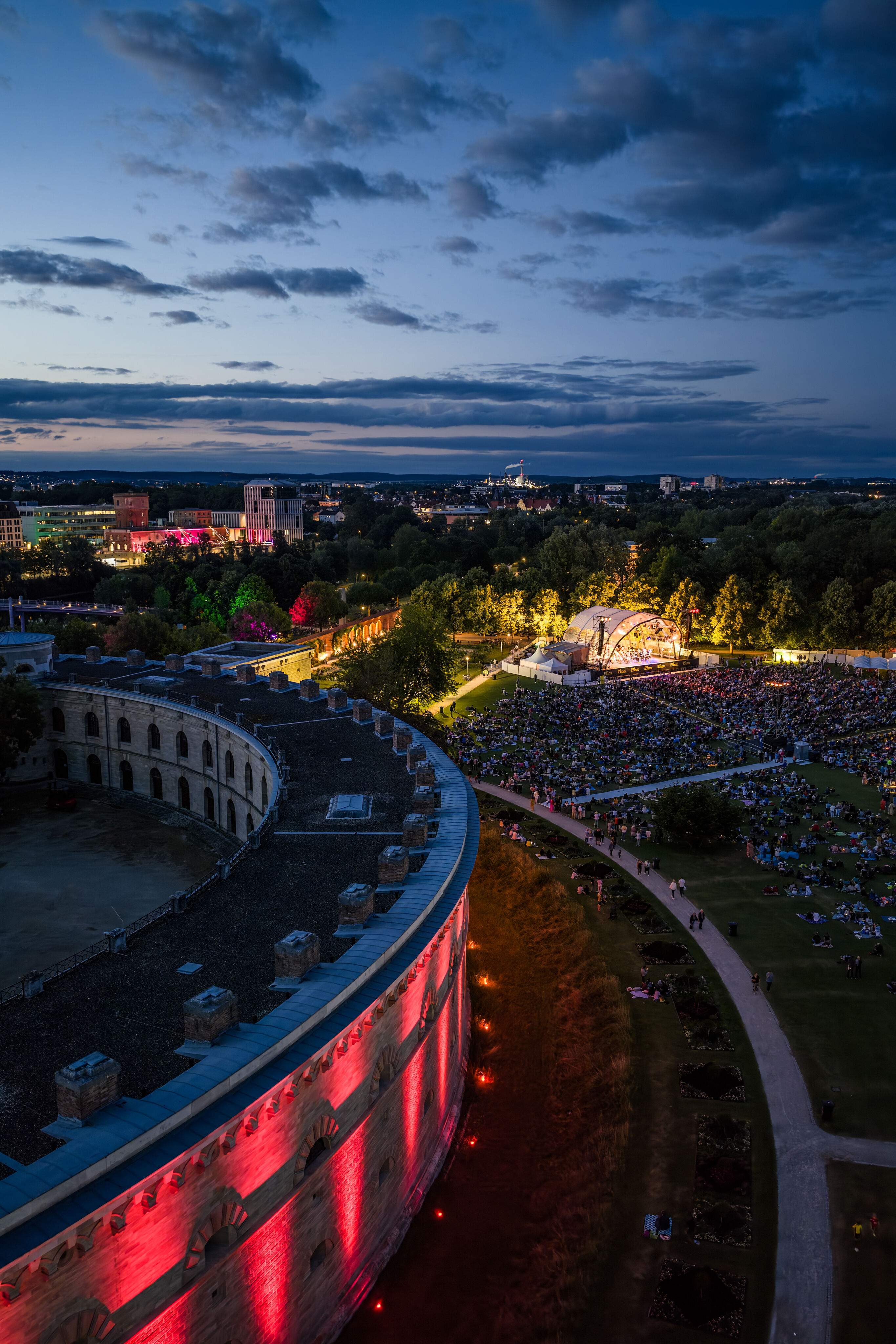 Classic Open Air – musical highlights with the Audi Philharmonic Wind Orchestra - Bird’s-eye view at dusk of the Classic Open Air event featuring the Audi Philharmonic Wind Orchestra as part of the Audi Summer Concerts in Klenzepark in Ingolstadt. In...