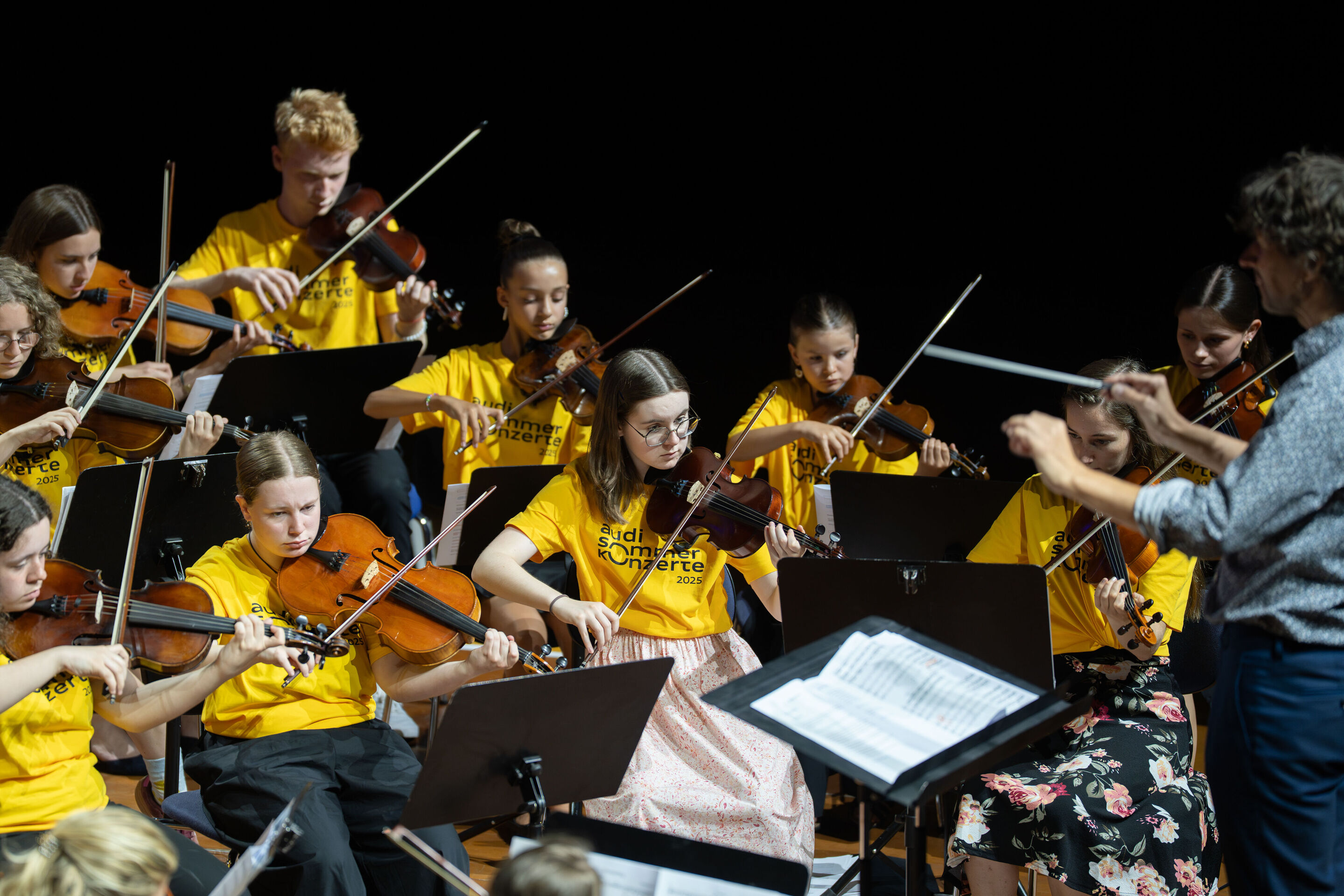 Public workshop with pupils from the region and the Aurora Orchestra - On the stage of the Ingolstadt festival hall, students from Ingolstadt high schools are making music together. On the right: Conductor Klaus Hoffmann.