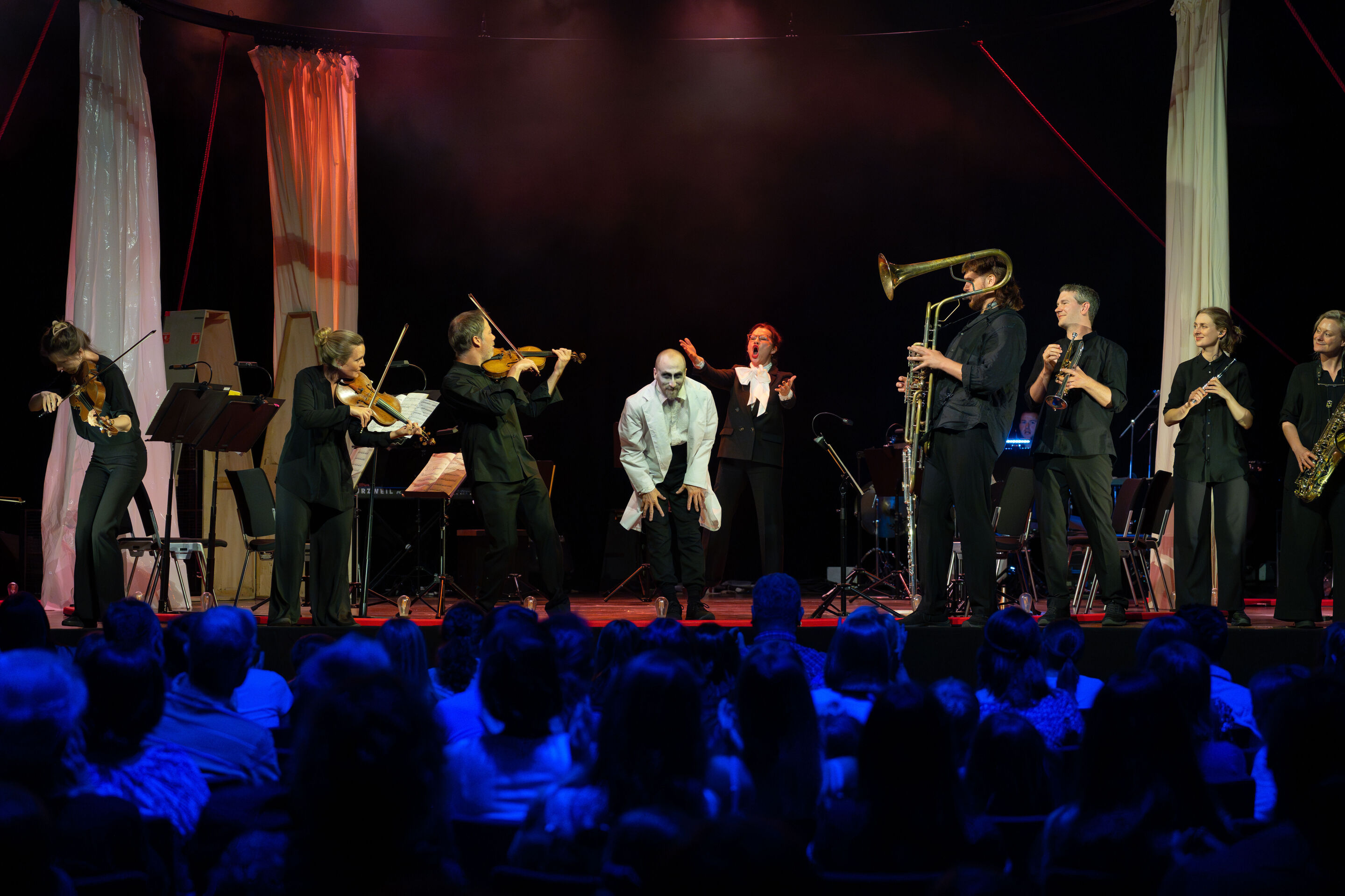 „Carnival“: Inszeniertes Familienkonzert rund um die fabelhafte Welt der Instrumente - Aus Sicht des Publikums verbeugt sich auf der Bühne des Festsaals Ingolstadt Tänzer Christopher Akrill, umrahmt von Musizierende des Aurora Orchestra. Hinter ihm ist...