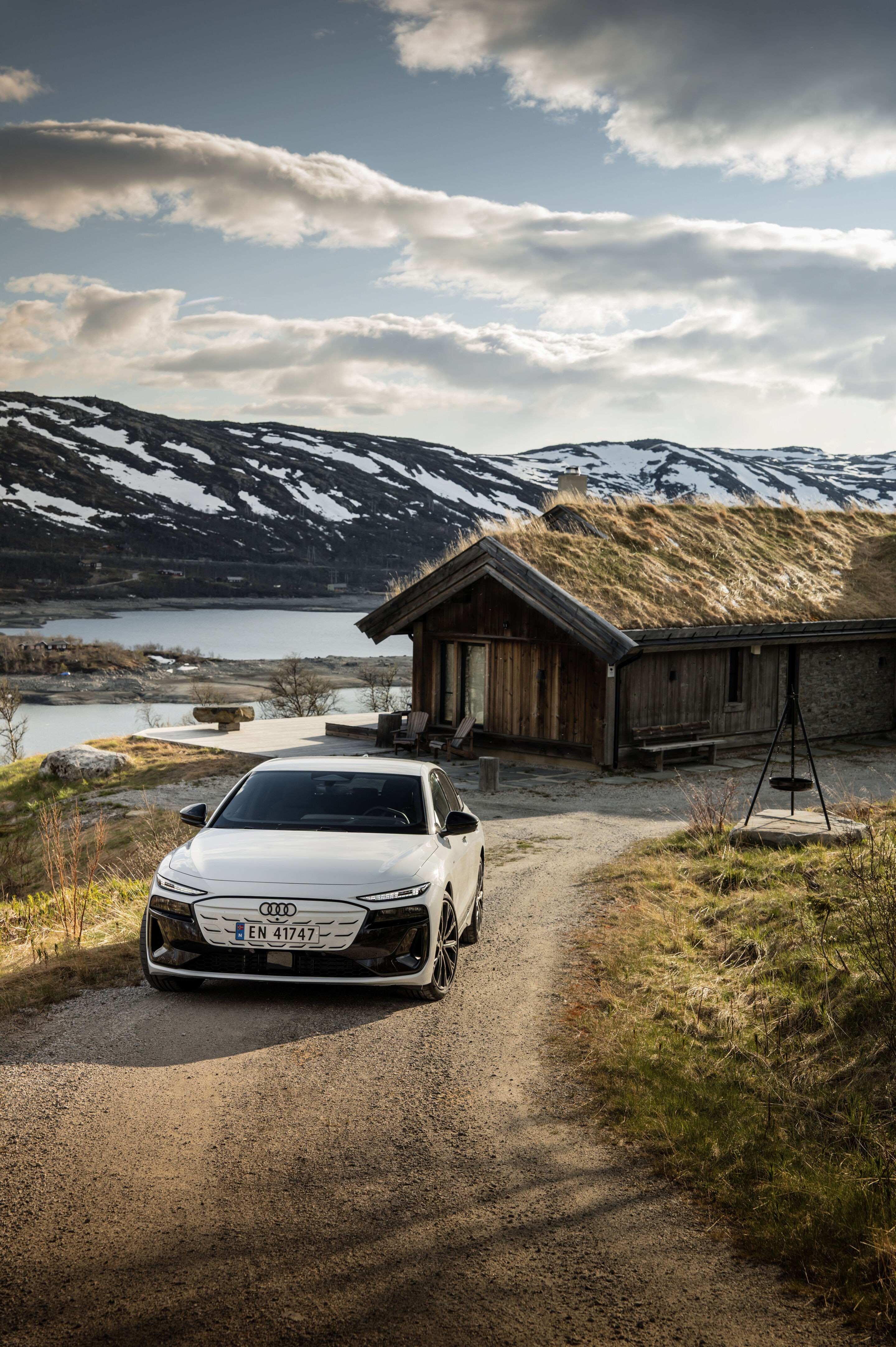 Strom aufwärts: Im Audi A6 e-tron von Kopenhagen nach Bergen - Ein Audi A6 Sportback e-tron in Gletscherweiß Metallic steht auf einem Schotterweg, der zu einem Haus klassischer skandinavischer Bauweise führt.