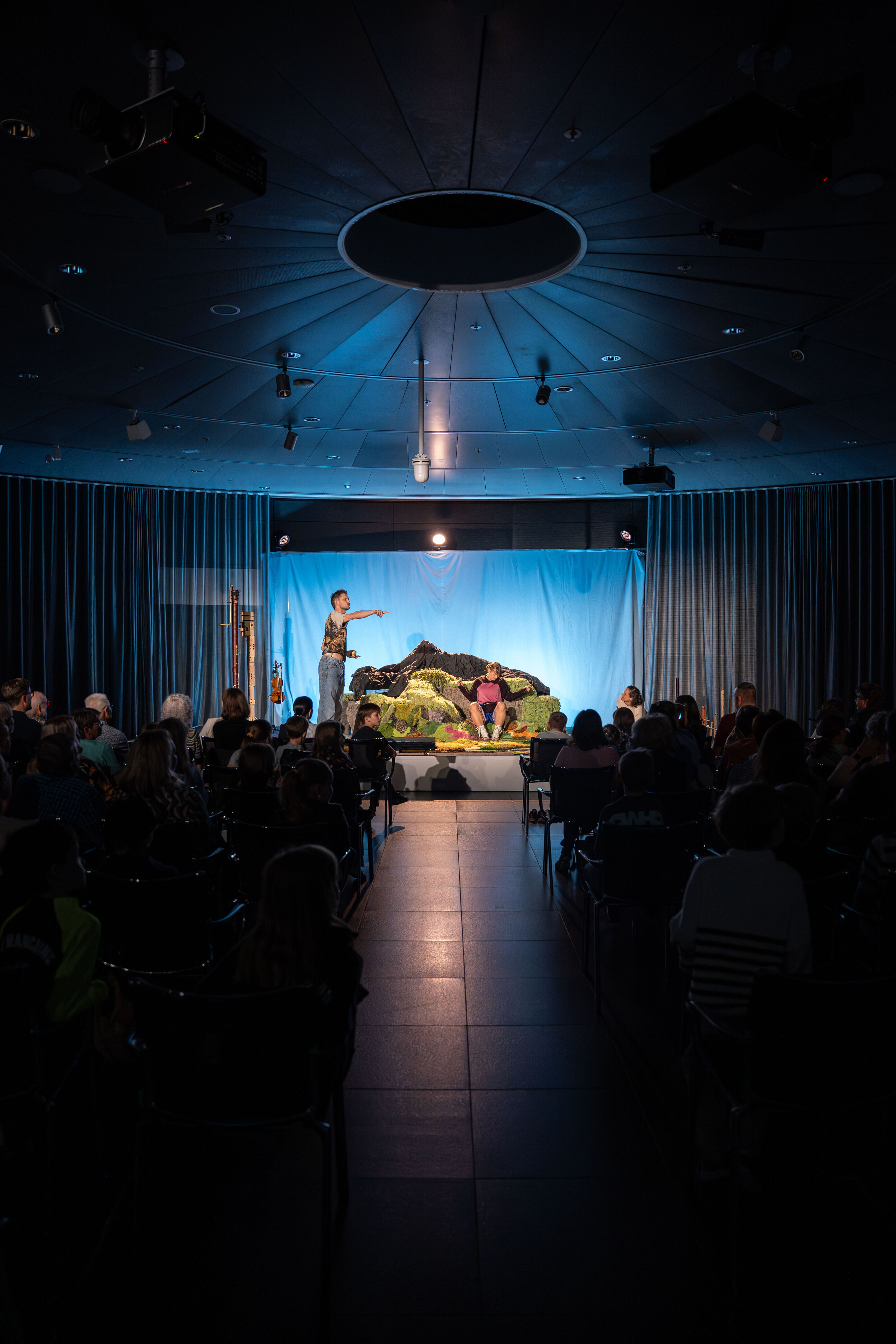 Salzburger Festspiele zu Gast: „Berge flüstern laut“ – Musiktheater für Kinder - Aus der Sicht des Publikums: Franca Luisa Burandt (l.) und Matteo Haitzmann (r.), Darsteller der Salzburgerfestspiele auf der Bühne des Kinosaals im Audi museum mobile.