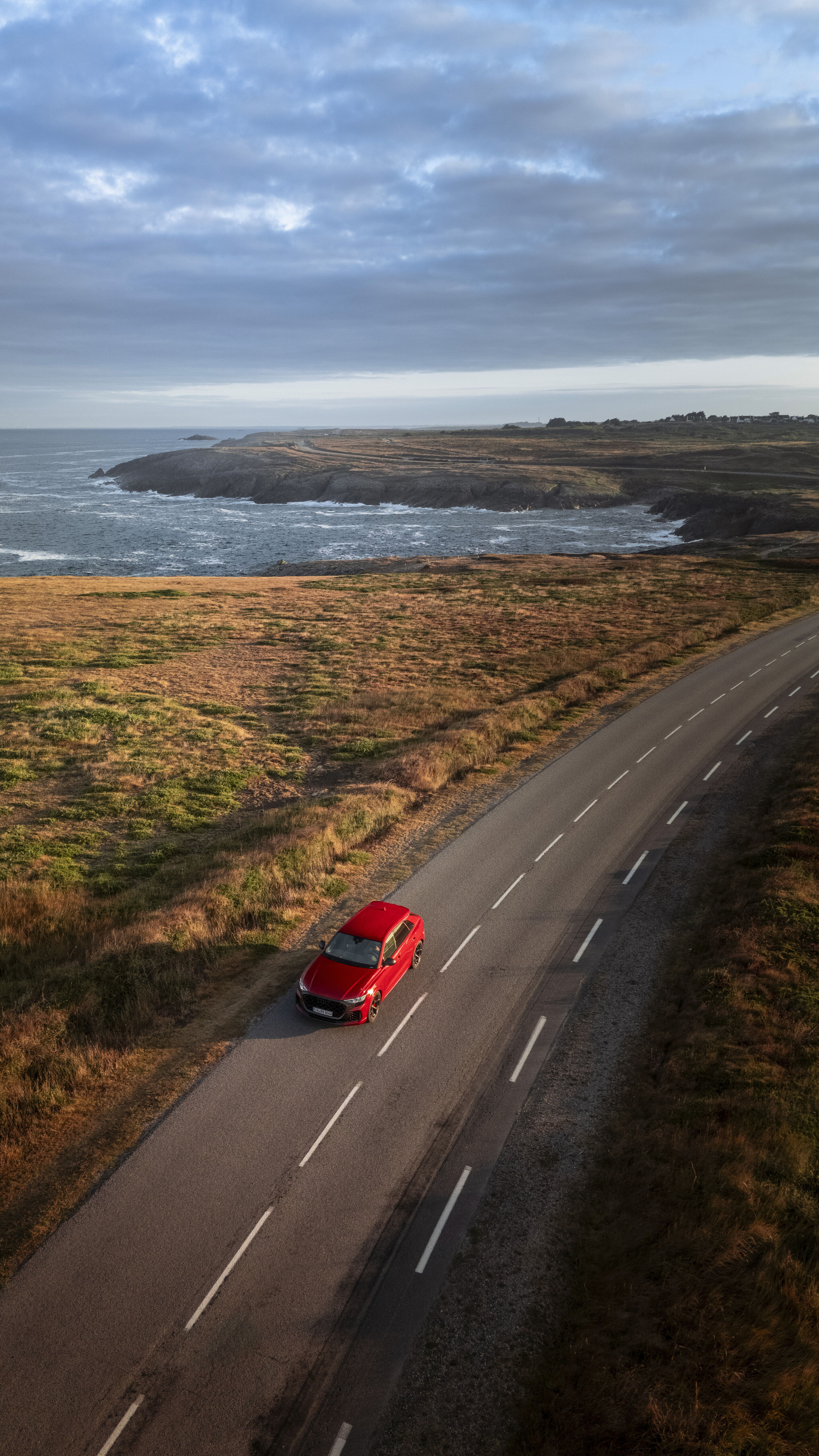 Audi RS Q8 SUV performance - Audi RS Q8 SUV performance in Chilirot Metallic auf einer Küstenstraße mit Blick auf das Meer.