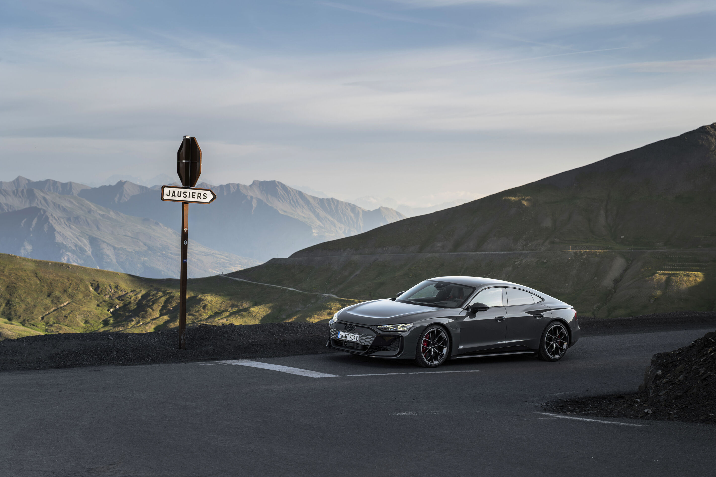 Audi RS e-tron GT quattro - Audi RS e-tron GT quattro in Nimbusgrau Perleffekt auf einer Bergstraße mit Blick auf umliegende Gipfel.