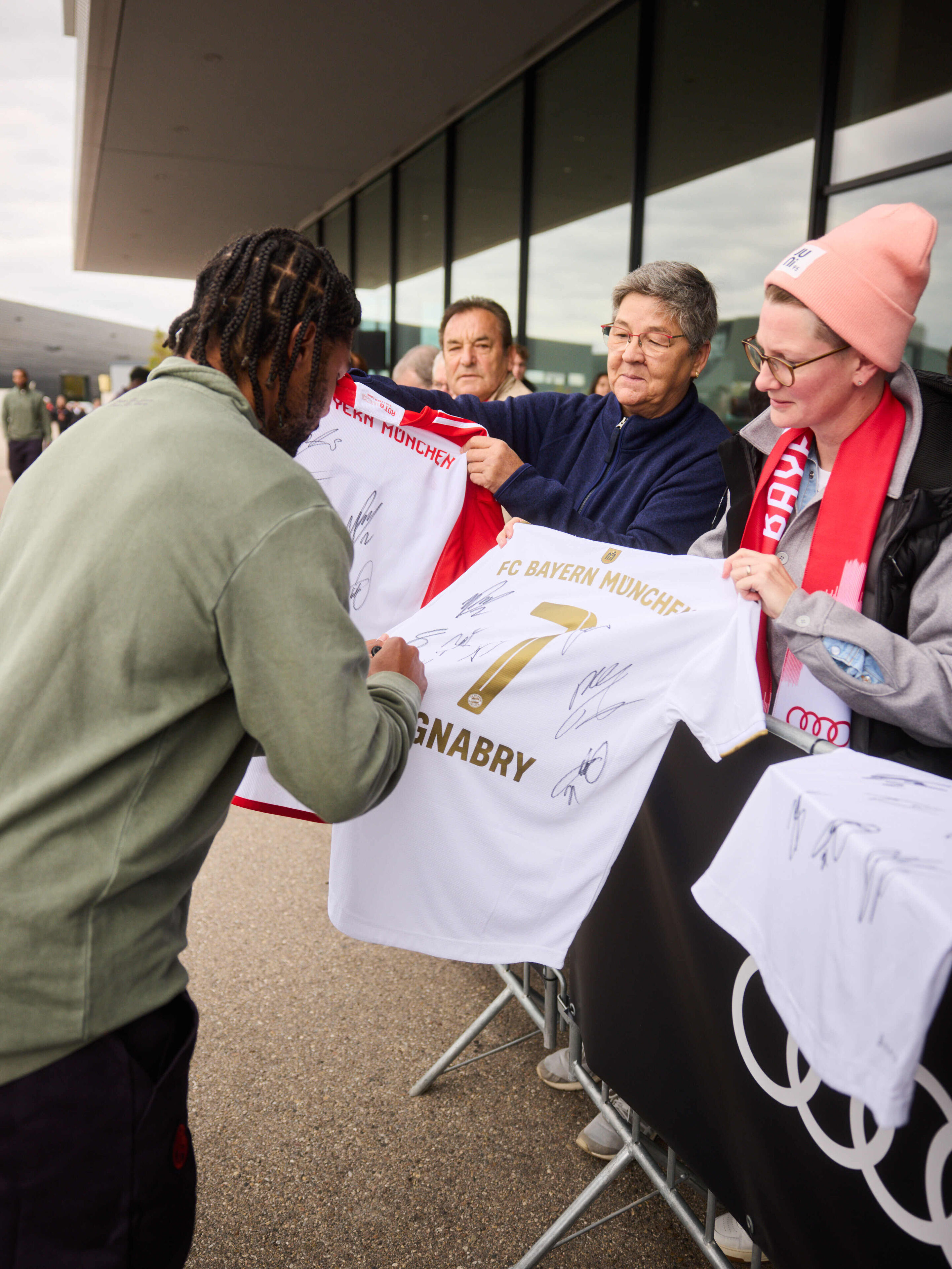 Audi übergibt neue Dienstwagen an FC Bayern München - Autogrammstunde bei der Fahrzeugübergabe: Serge Gnabry signiert ein FC Bayern Trikot für glückliche Audi Mitarbeitende.