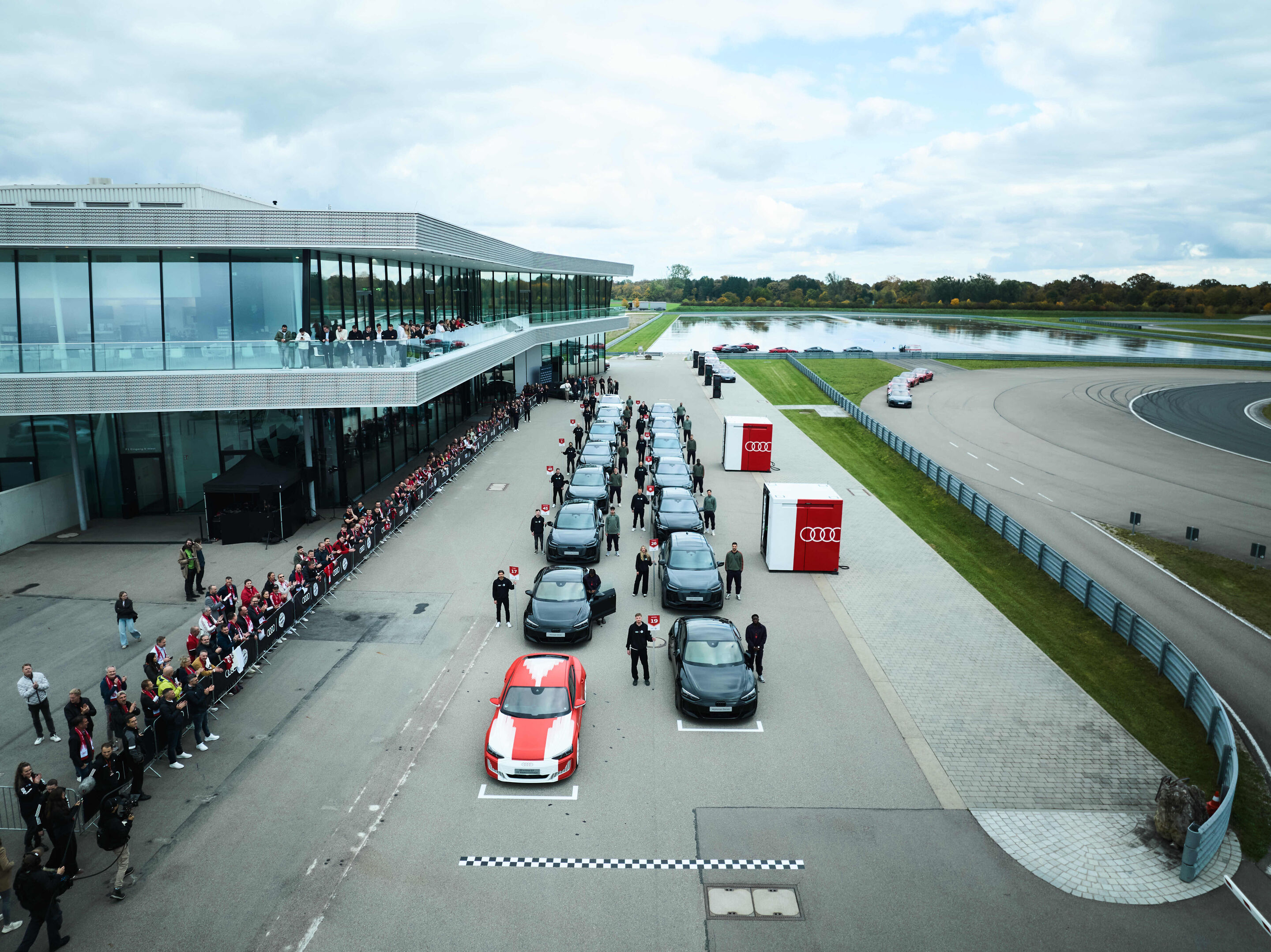 Audi übergibt neue Dienstwagen an FC Bayern München - Die Dienstwagen für die Profis des FC Bayern stehen in Rennaufstellung bereit, darunter ein RS e-tron GT performance foliert in den Farben des neuen FCB-Trikots.