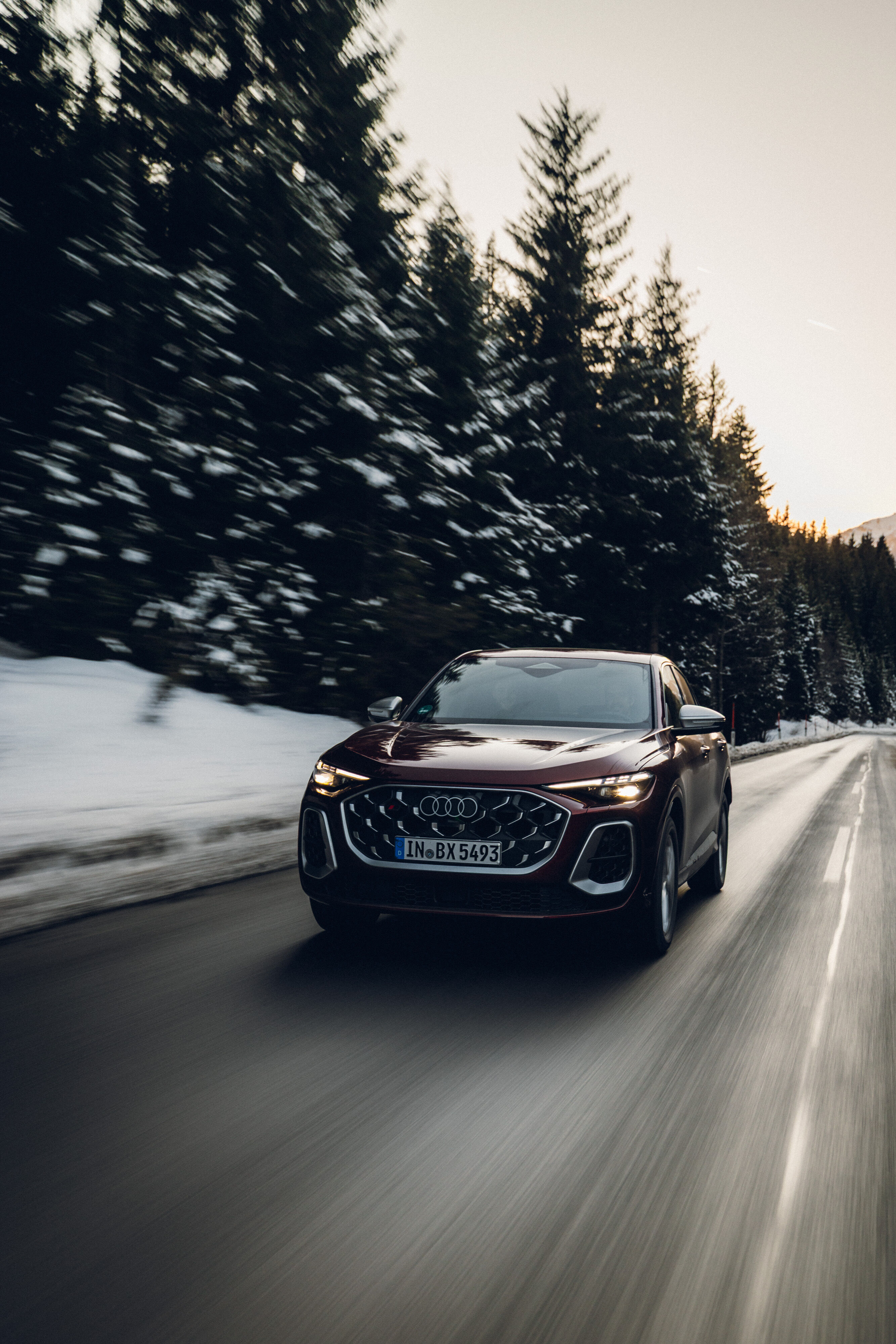 Audi SQ5 Sportback - Ein Audi SQ5 Sportback in Grenadinerot fährt auf einer winterlichen Bergstraße. Die Straße ist von Schnee gesäumt.