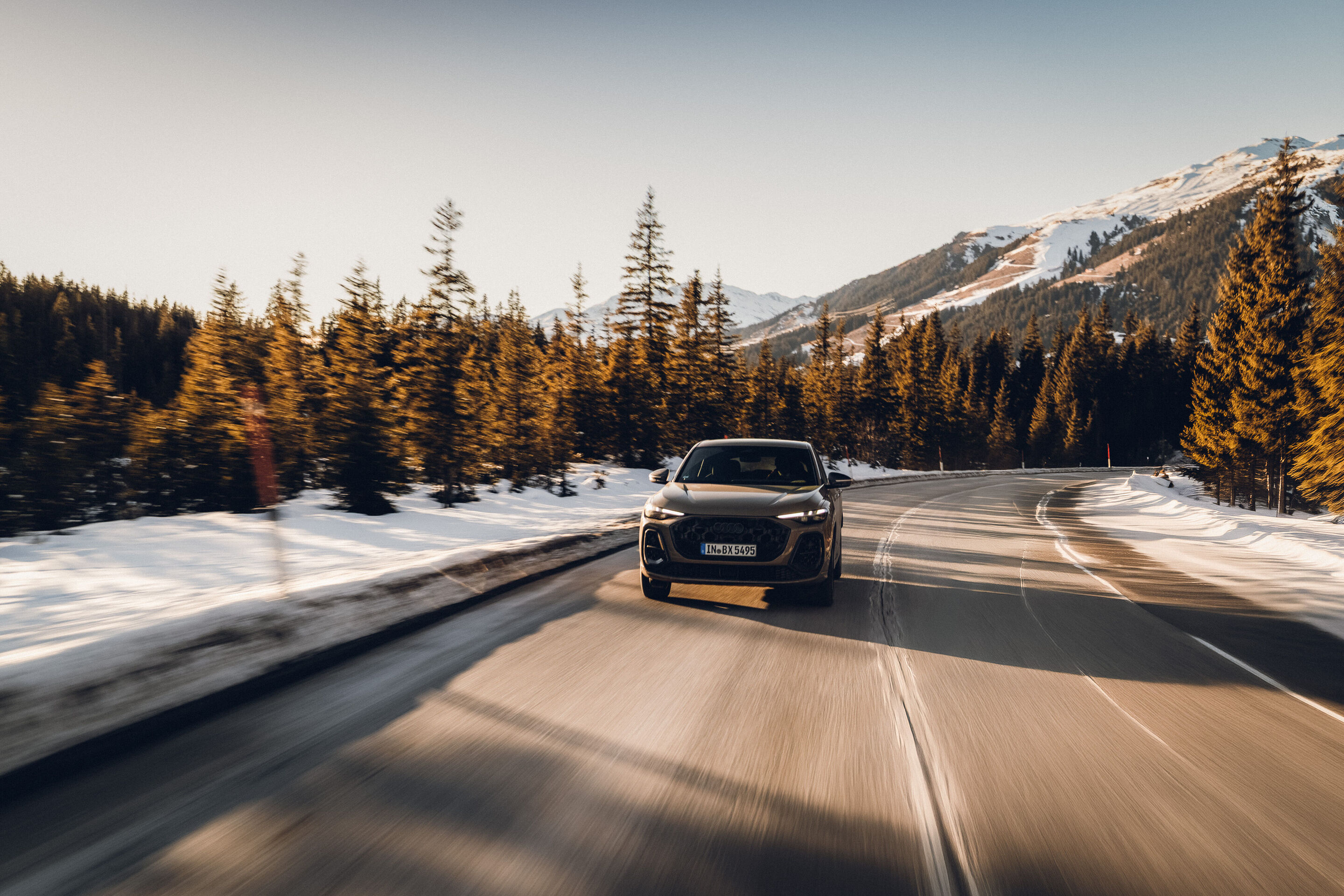 Audi Q5 Sportback - An Audi Q5 Sportback in Sakhir Gold is driving along a winter mountain road. Snow lines the roadside