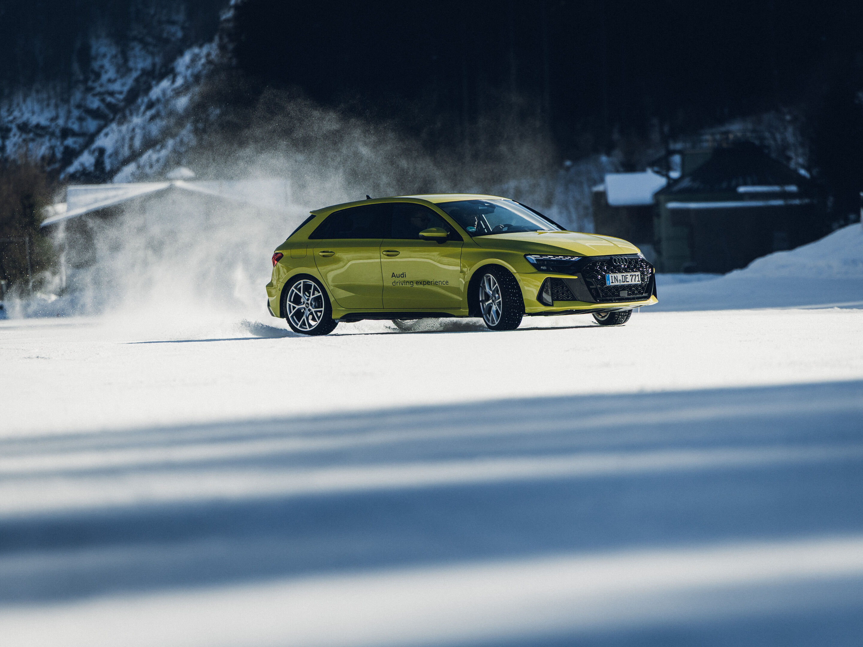 Audi RS 3 Sportback - Ein Audi RS 3 Sportback in Pythongelb fährt auf einer verschneiten Fläche und wirbelt Schnee auf.