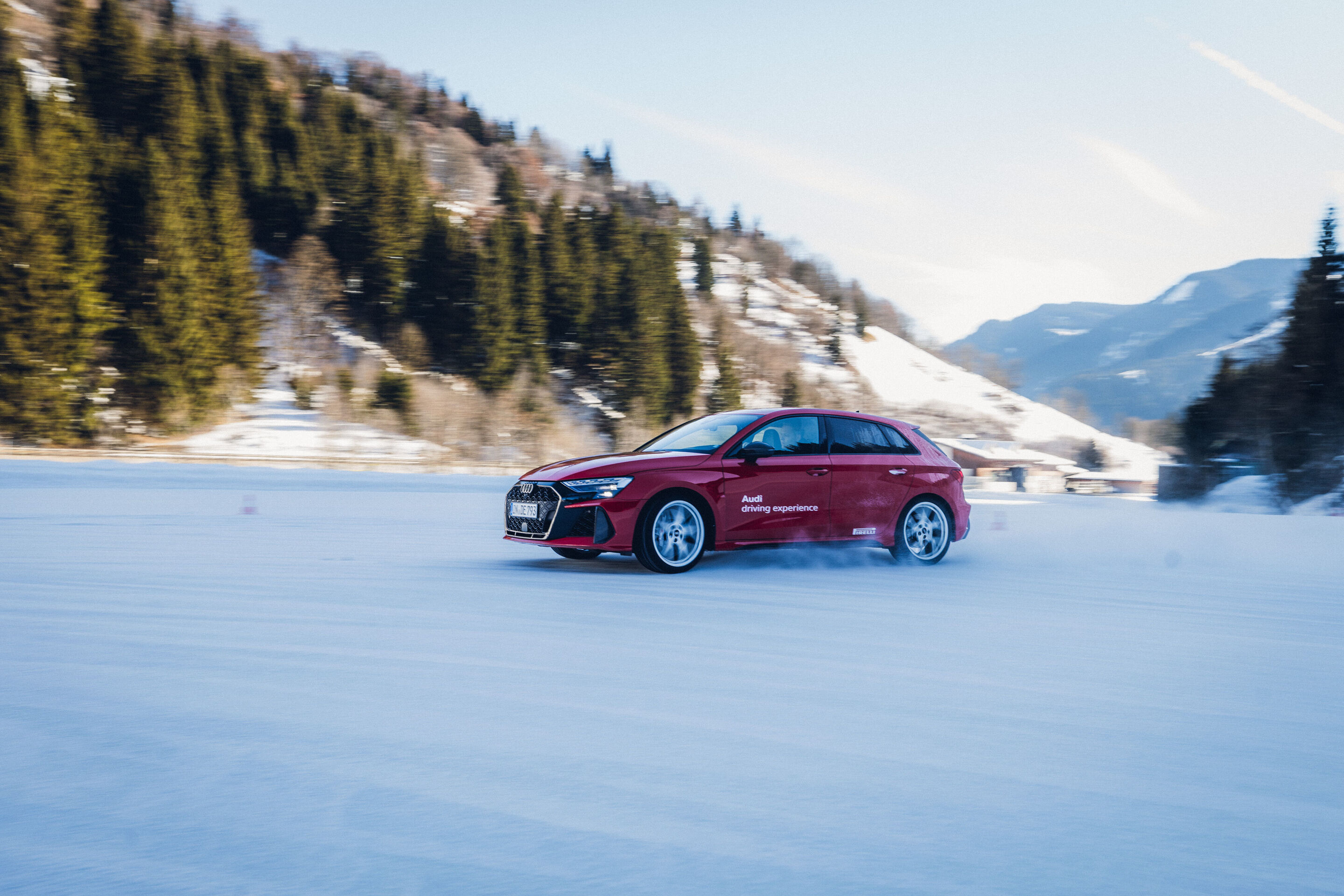 Audi RS 3 Sportback - Ein Audi RS 3 Sportback in Progressivrot fährt auf einer verschneiten Fläche und wirbelt Schnee auf.