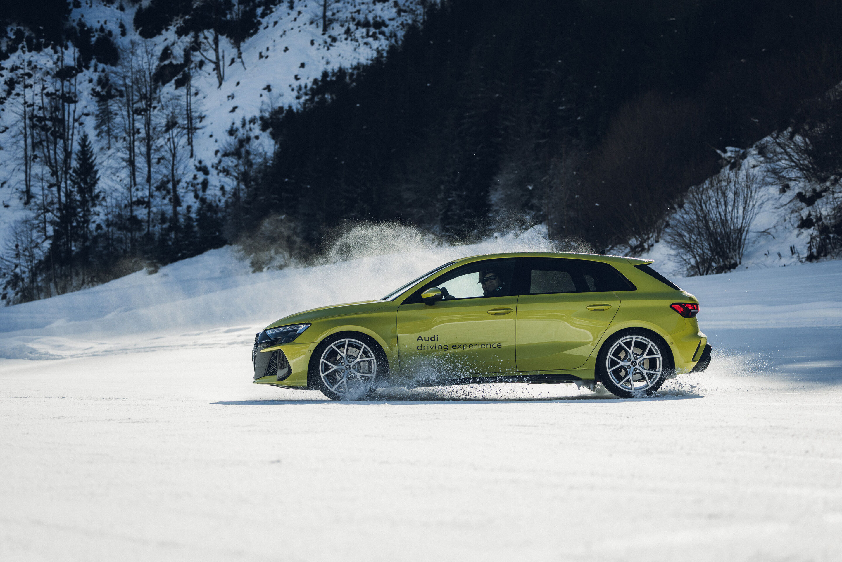 Audi RS 3 Sportback - Ein Audi RS 3 Sportback in Pythongelb fährt auf einer verschneiten Fläche und wirbelt Schnee auf.