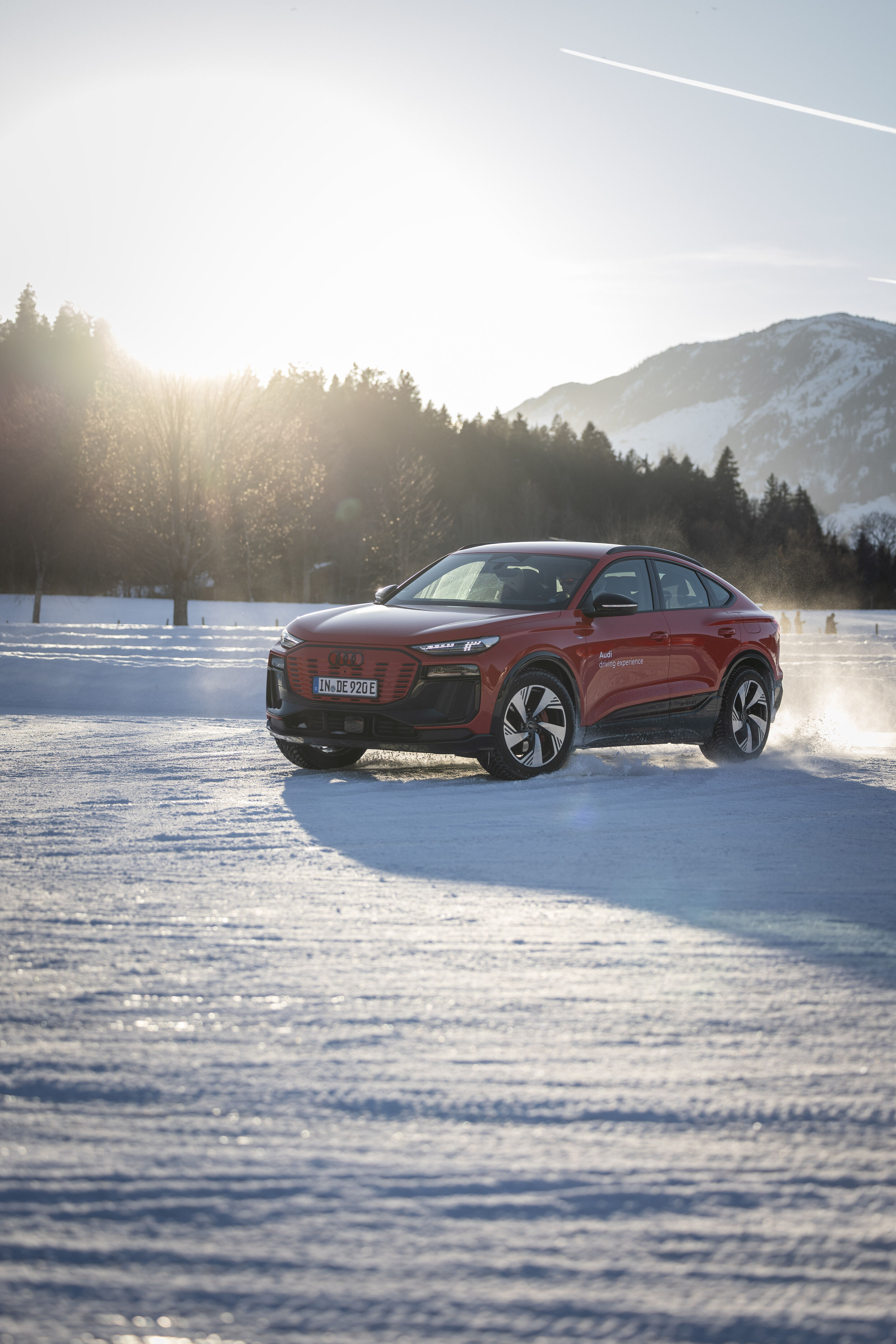 Audi Q6 Sportback e-tron - Der Audi Q6 Sportback e-tron fährt über eine schneebedeckte Fläche, im Hintergrund Wald und verschneite Berge.
Farbe: Progressivrot Metallic, Outdoor Fahraufnahme, Exterieur, Dreiviertelfrontansicht