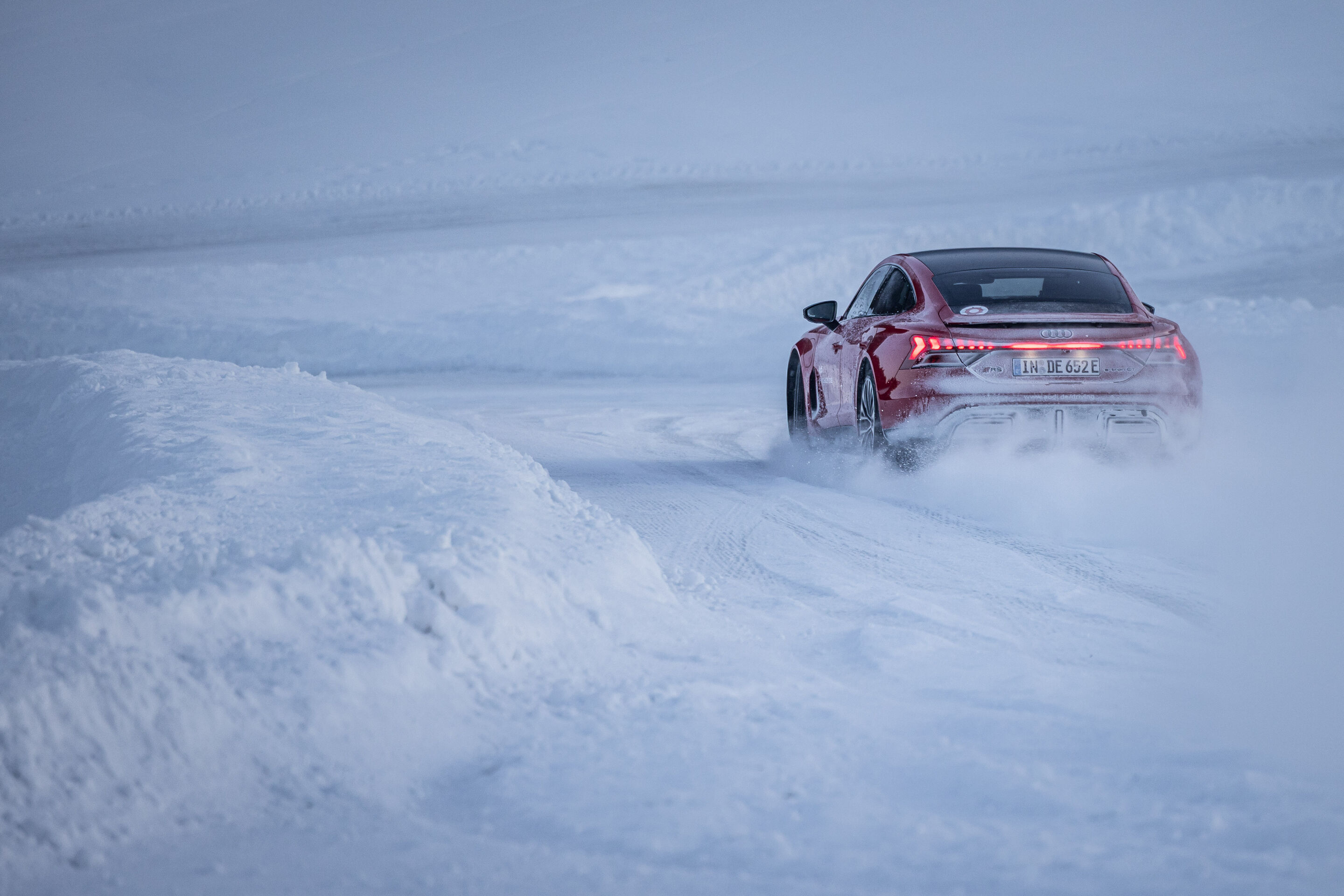 Audi RS e-tron GT - Der Audi RS e-tron GT auf einer schneebedeckten Teststrecke und wirbelt dabei feinen Schnee hinter sich auf.
Farbe: Progressivrot Metallic, Outdoor Fahraufnahme, Exterieur, Dreiviertelfheckansicht