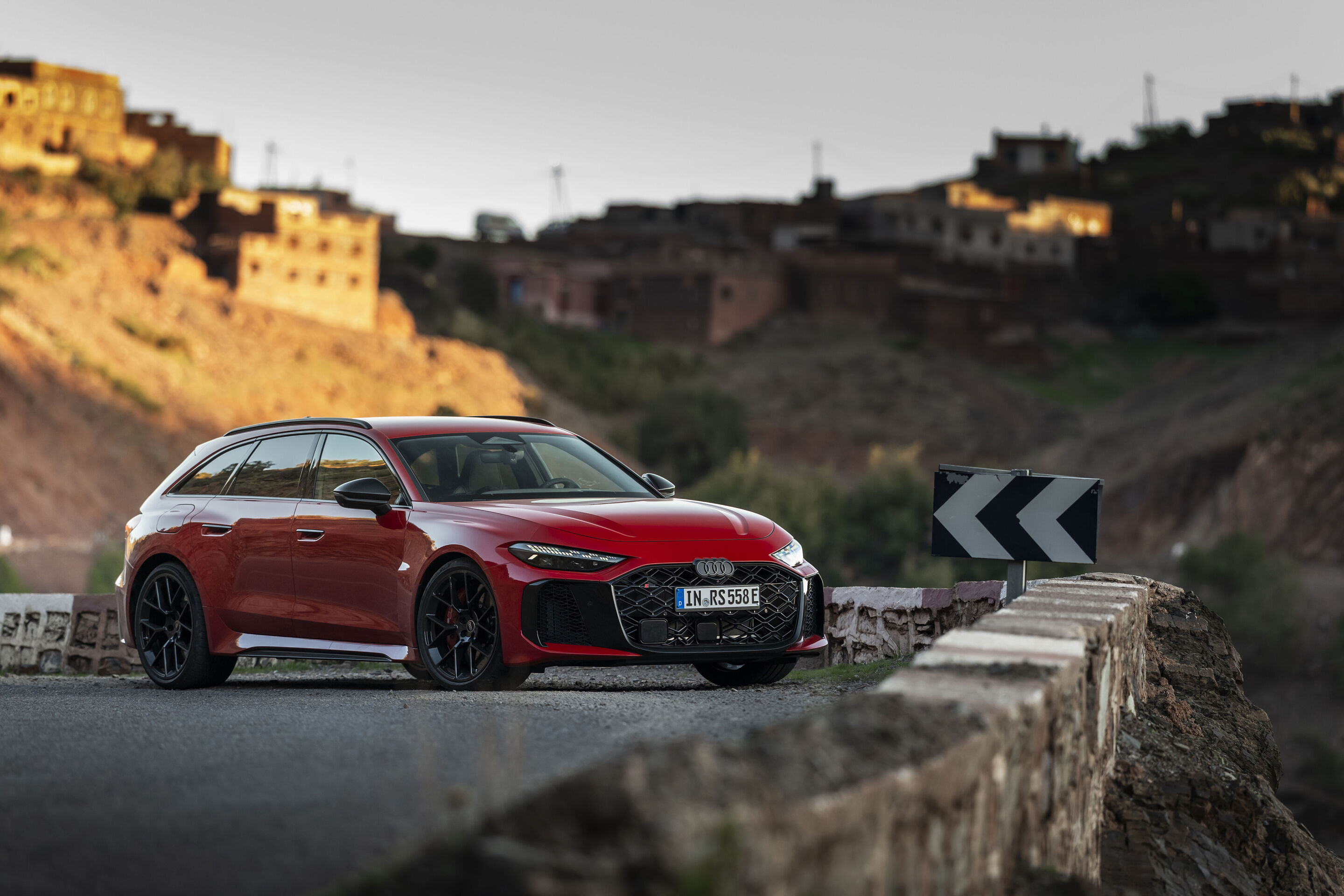 Audi RS 5 Avant - Der Audi RS 5 Avant in Progressivrot auf einer kurvigen Bergstraße nahe eines marokkanischen Gebirgsdorfs – präzise Fahrdynamik auf anspruchsvollem Terrain.