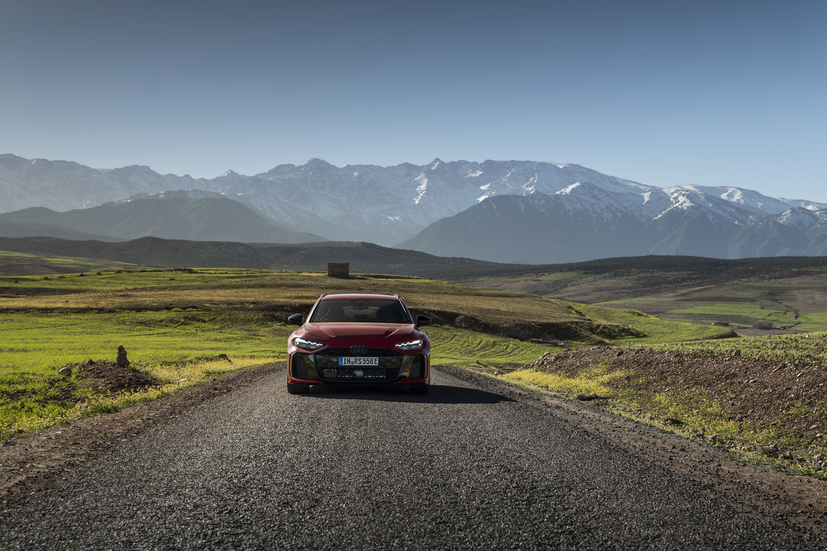Audi RS 5 Avant - The Audi RS 5 Avant in Progressiv red on a high‑altitude road overlooking snow‑capped Atlas peaks: electric efficiency meets confident performance.
