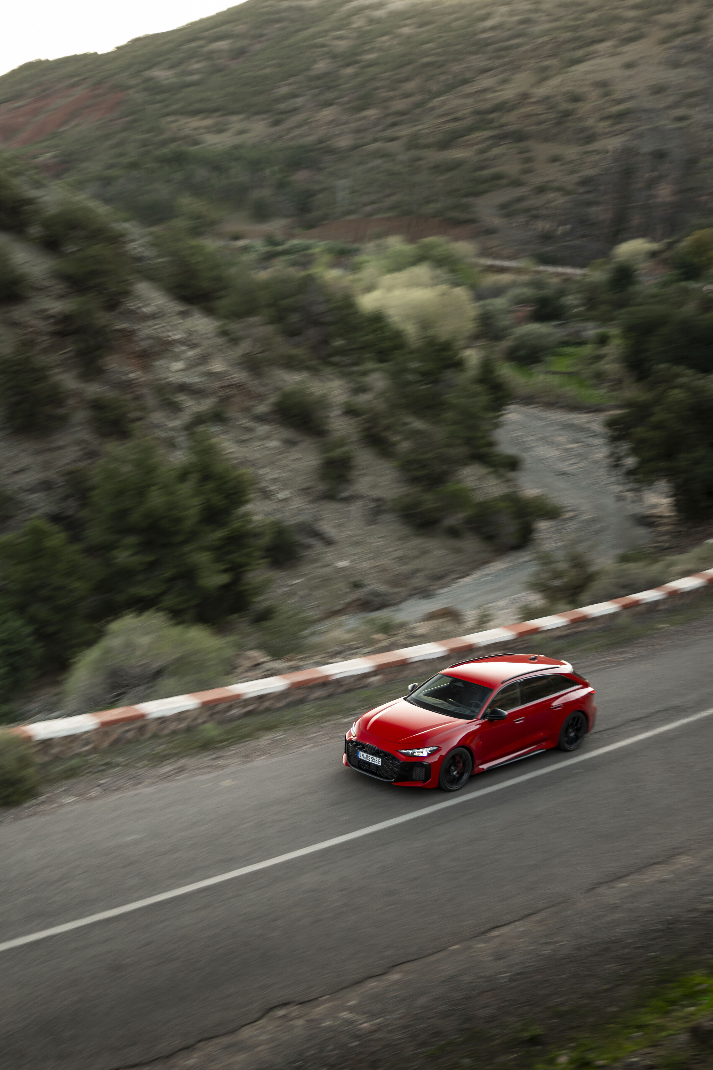Audi RS 5 Avant - The Audi RS 5 Avant in Progressiv red on a descending mountain road: stable cornering performance and agile handling on varying surfaces.