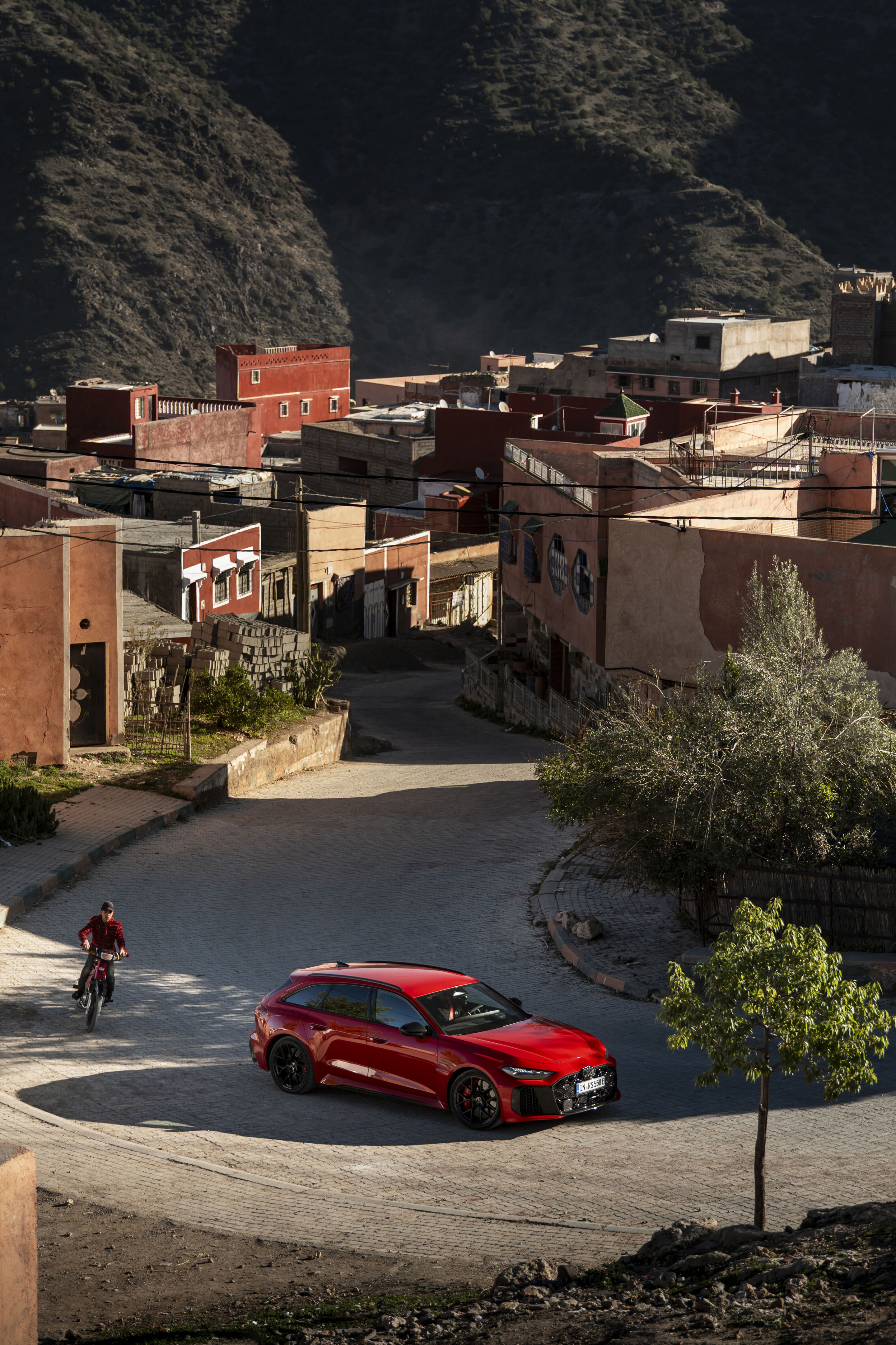 Audi RS 5 Avant - The Audi RS 5 Avant in Progressiv red navigating a narrow village passage in the Atlas Mountains – quiet in electric mode, powerful on steep gradients.