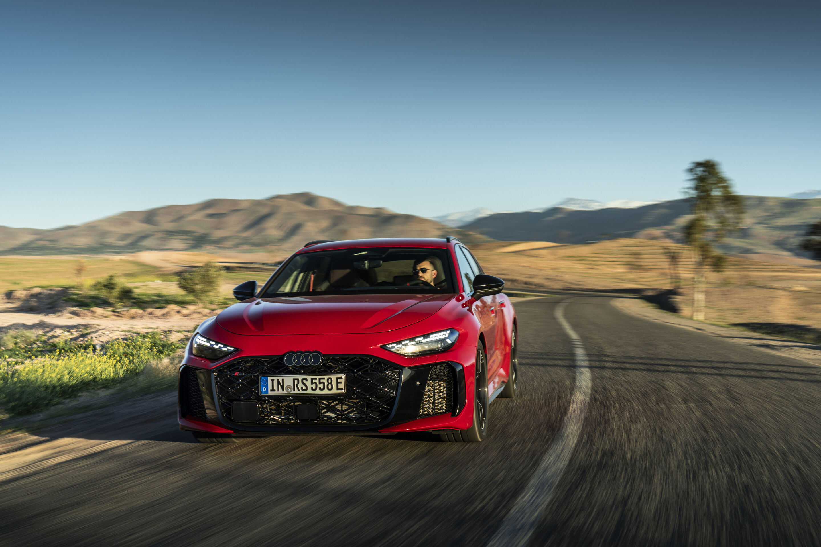 Audi RS 5 Avant - The Audi RS 5 Avant in Progressiv red on a winding mountain road – sporty driving dynamics in demanding surroundings.