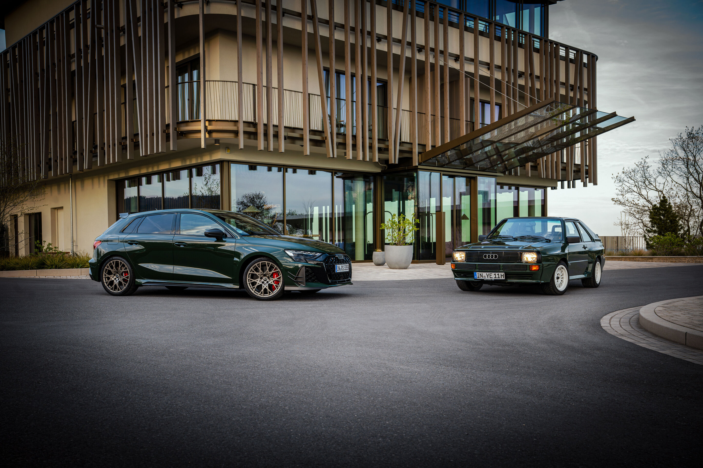 50 Jahre Fünfzylinder - Ein Audi RS3 competition limited steht neben einem historischen Audi Sport quattro von 1984 vor zeitgenössischer Architektur.