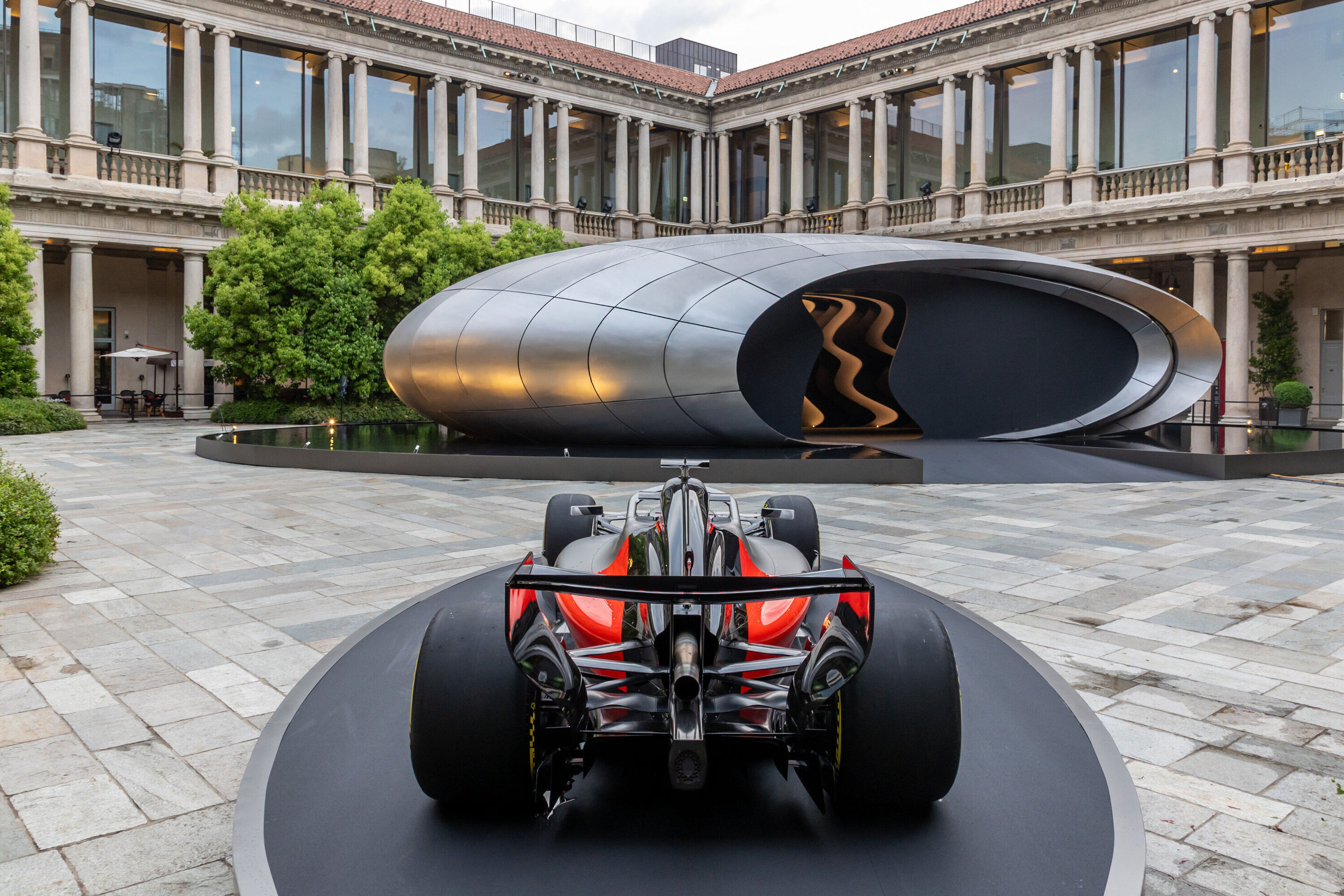 Audi auf der Milan Design Week 2026 - Rückansicht des Audi Formel‑1‑Showcars Audi R26 auf einer runden Präsentationsplattform. Im Hintergrund die Installation „Origin“ von Audi.