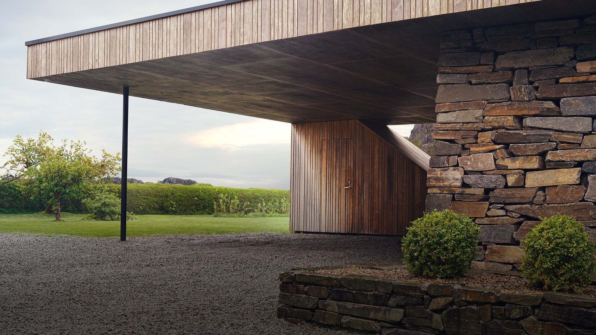 Eckansicht eines Hauses mit Natursteinwänden und einem holzverkleideten Carport. - Eckansicht eines Hauses mit Natursteinwänden und einem holzverkleideten Carport.