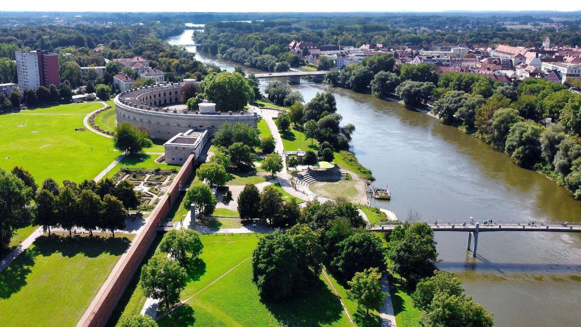 Ingolstadt in Vogelperspektive mit einem Fluss, Gebäuden und Wiesen mit Bäumen
