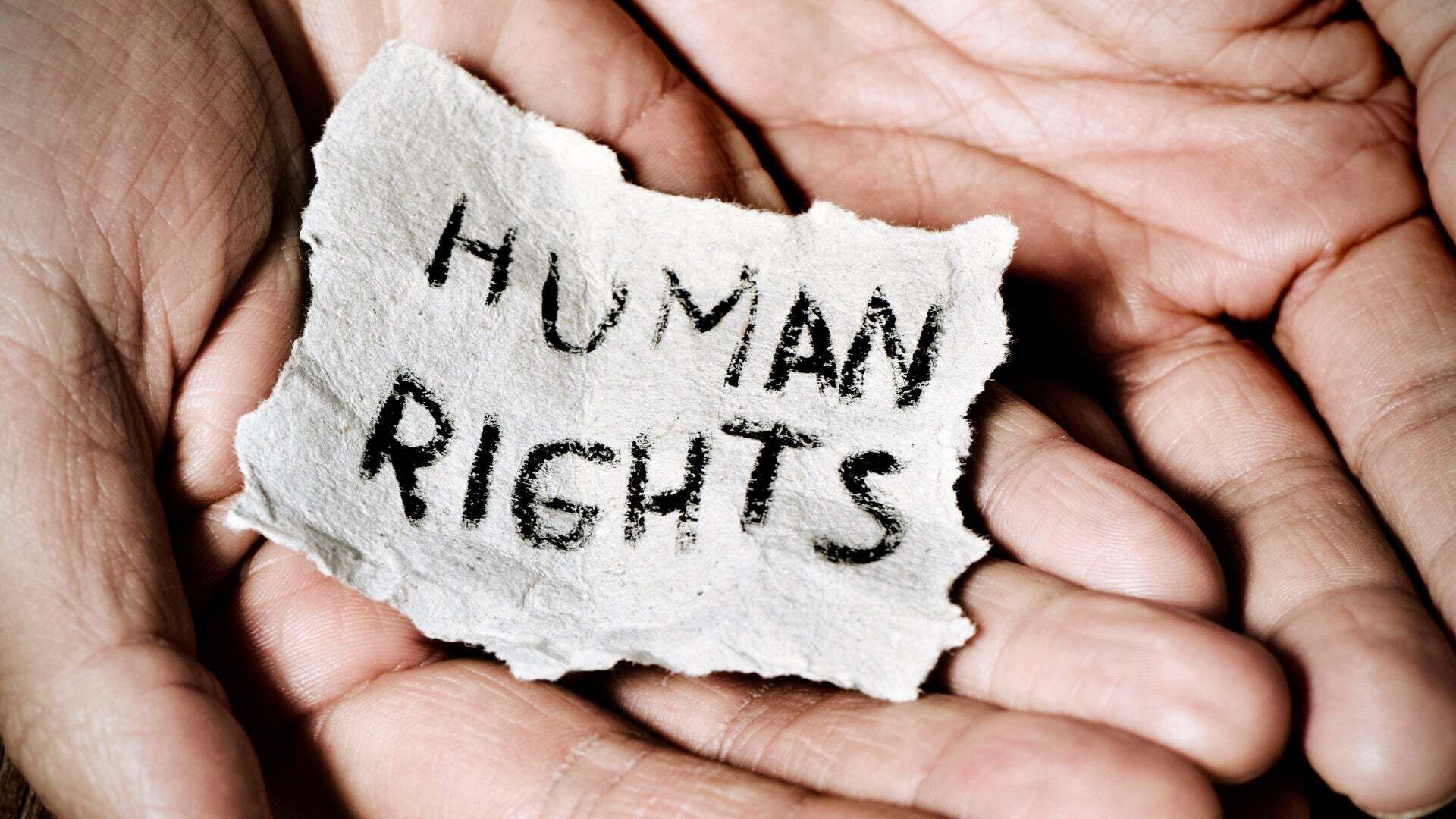 Hände halten einen Zettel mit der Aufschrift Human Rights