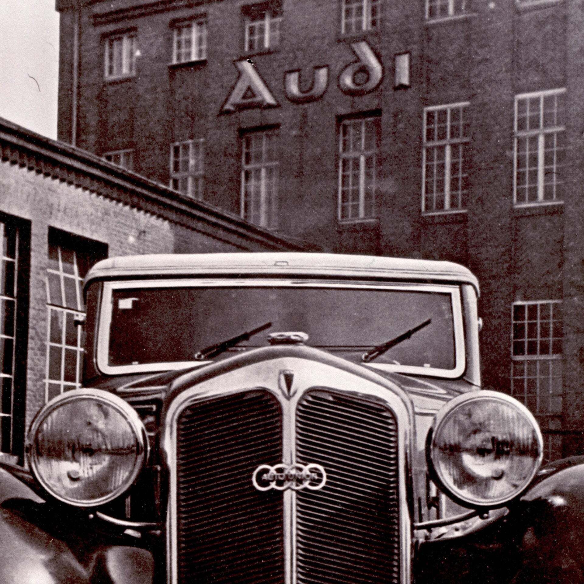 Nahaufnahme eines Audi Traditionsmodells vor einem historischen Audi Werk - Nahaufnahme eines Audi Traditionsmodells vor einem historischen Audi Werk