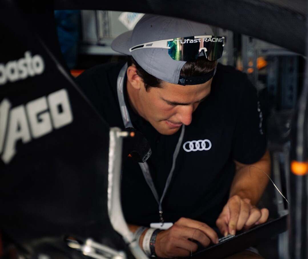Formula Student - A person stands at the door of a vehicle and holds a device in his hand that he is looking at
