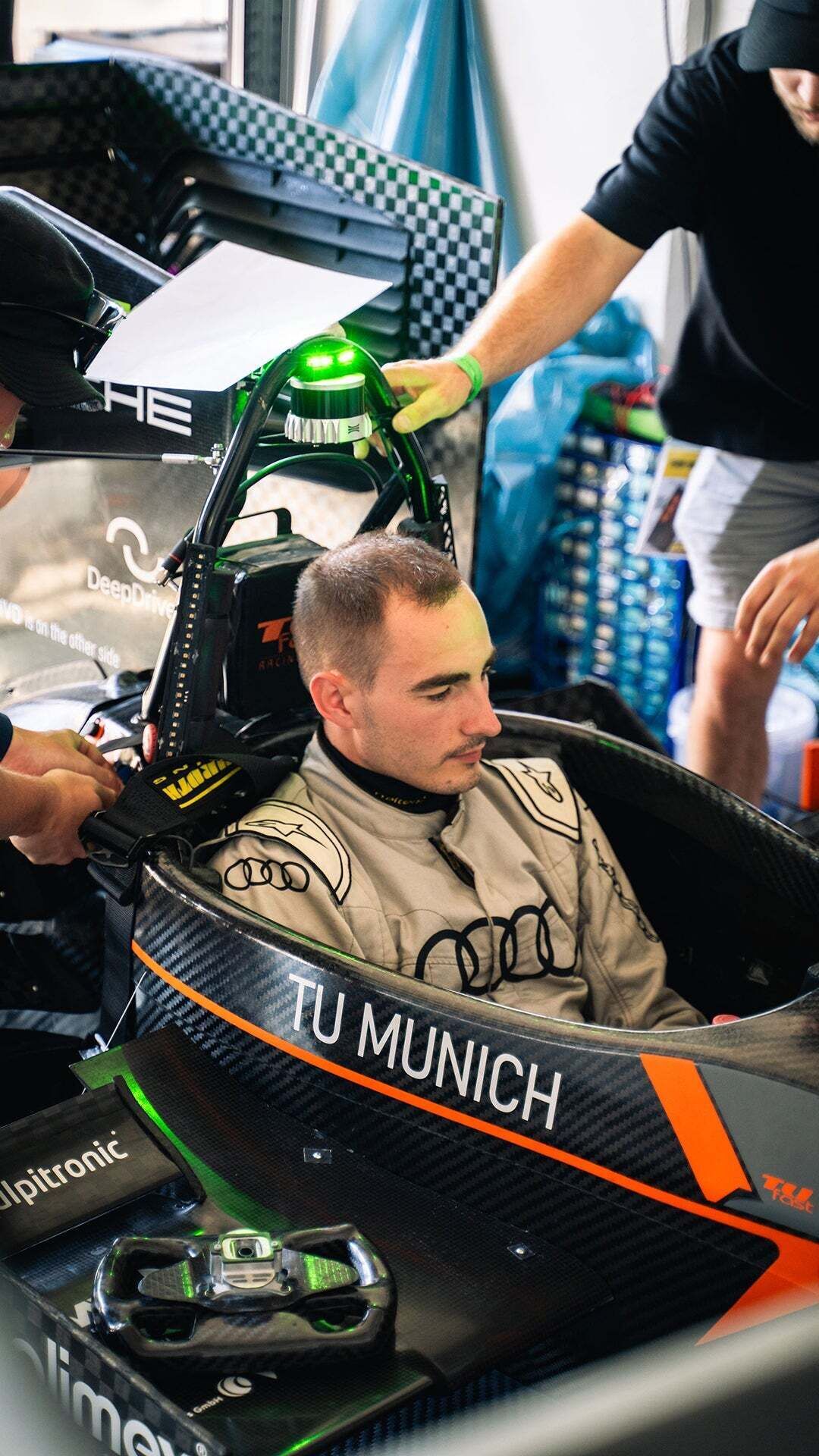 Formula Student - A man sits in a racing car while two other people work on the car