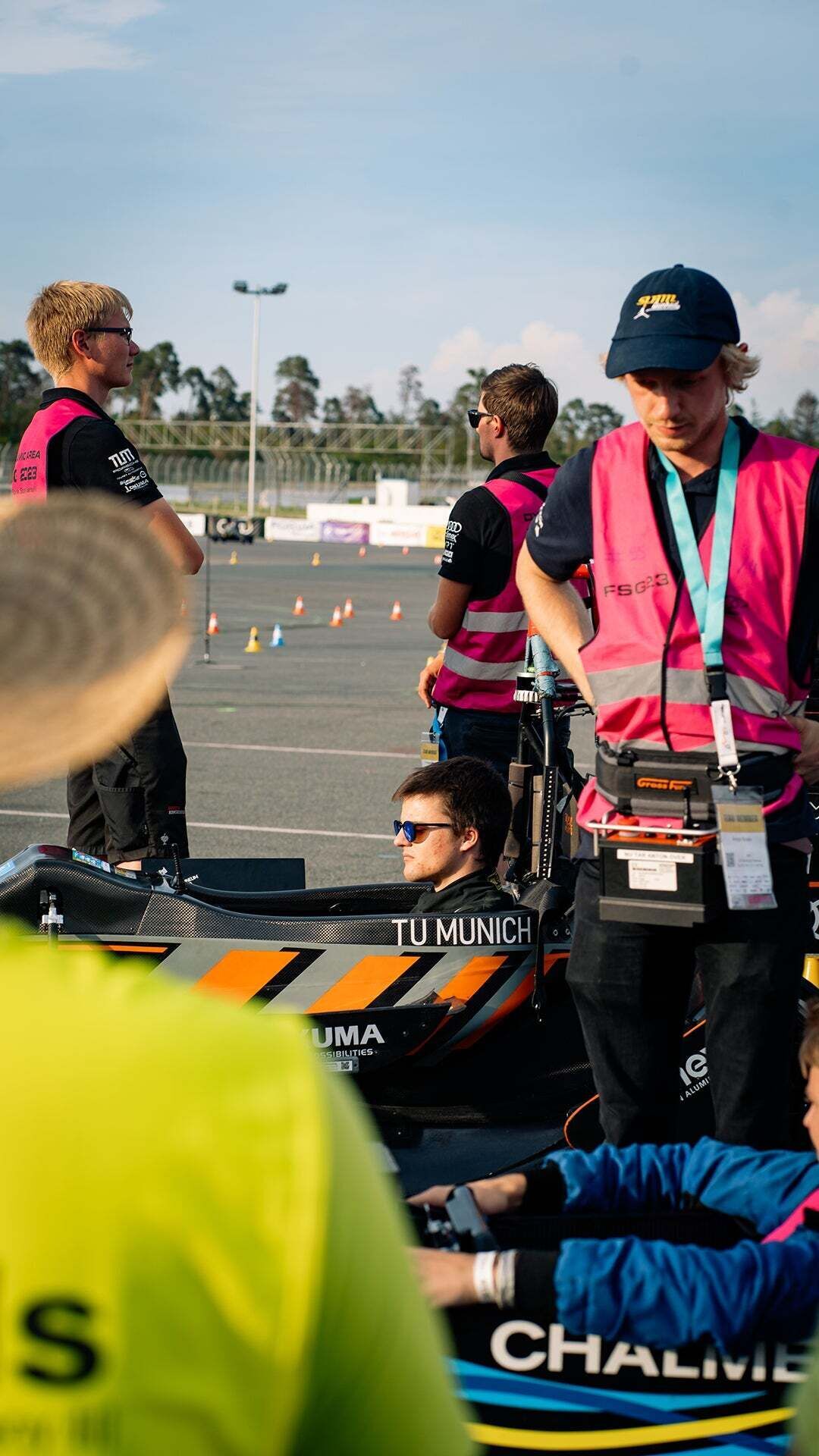 Formula Student - A few people stand on a training ground while two people sit in racing cars