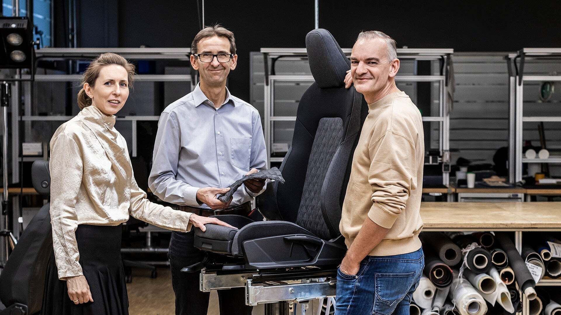 Christine Maier, Jürgen Frank, and Günther Ernst are standing in a workshop next to an Audi car seat.