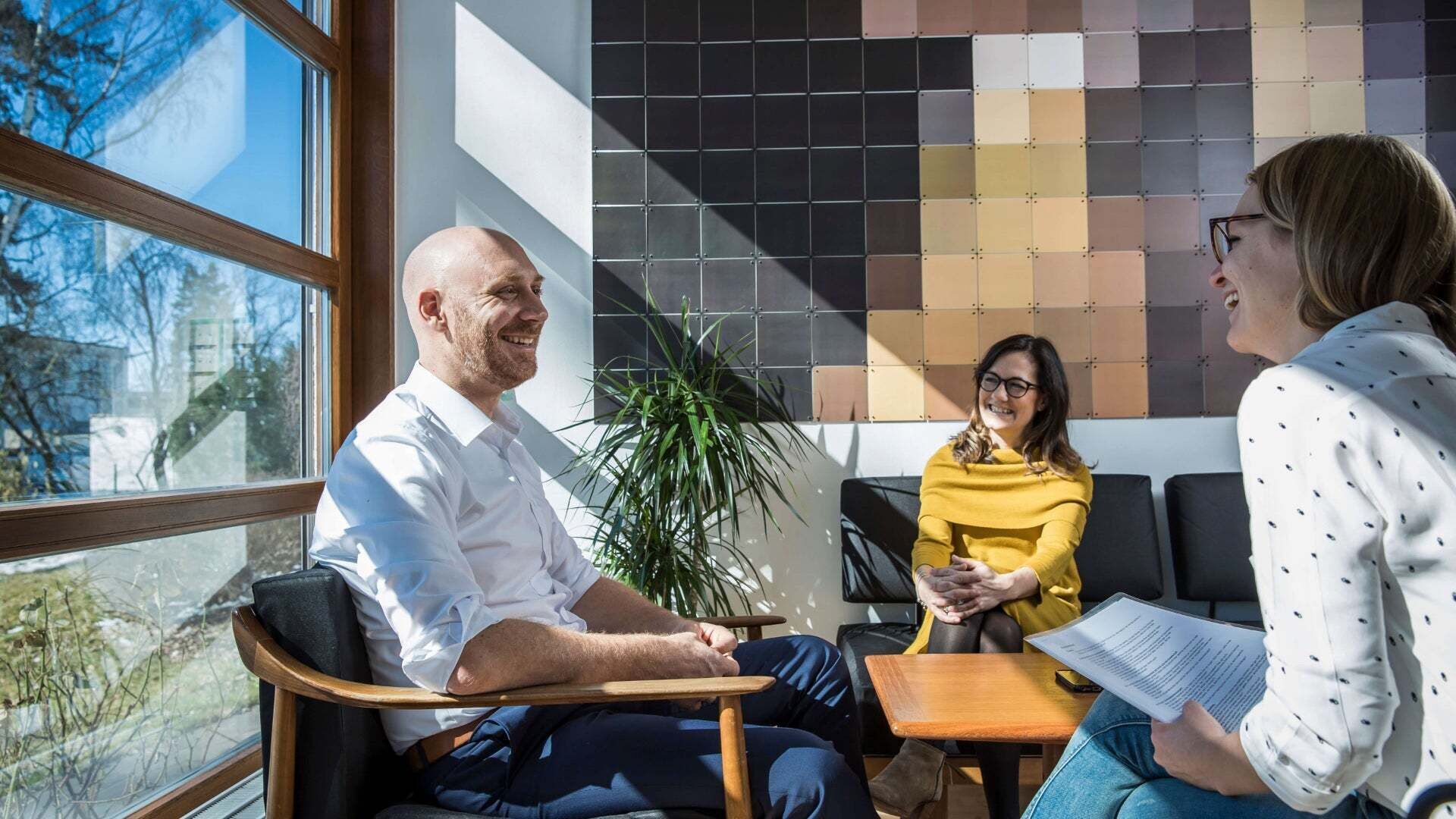 Three people are sitting around a table and chatting happily.