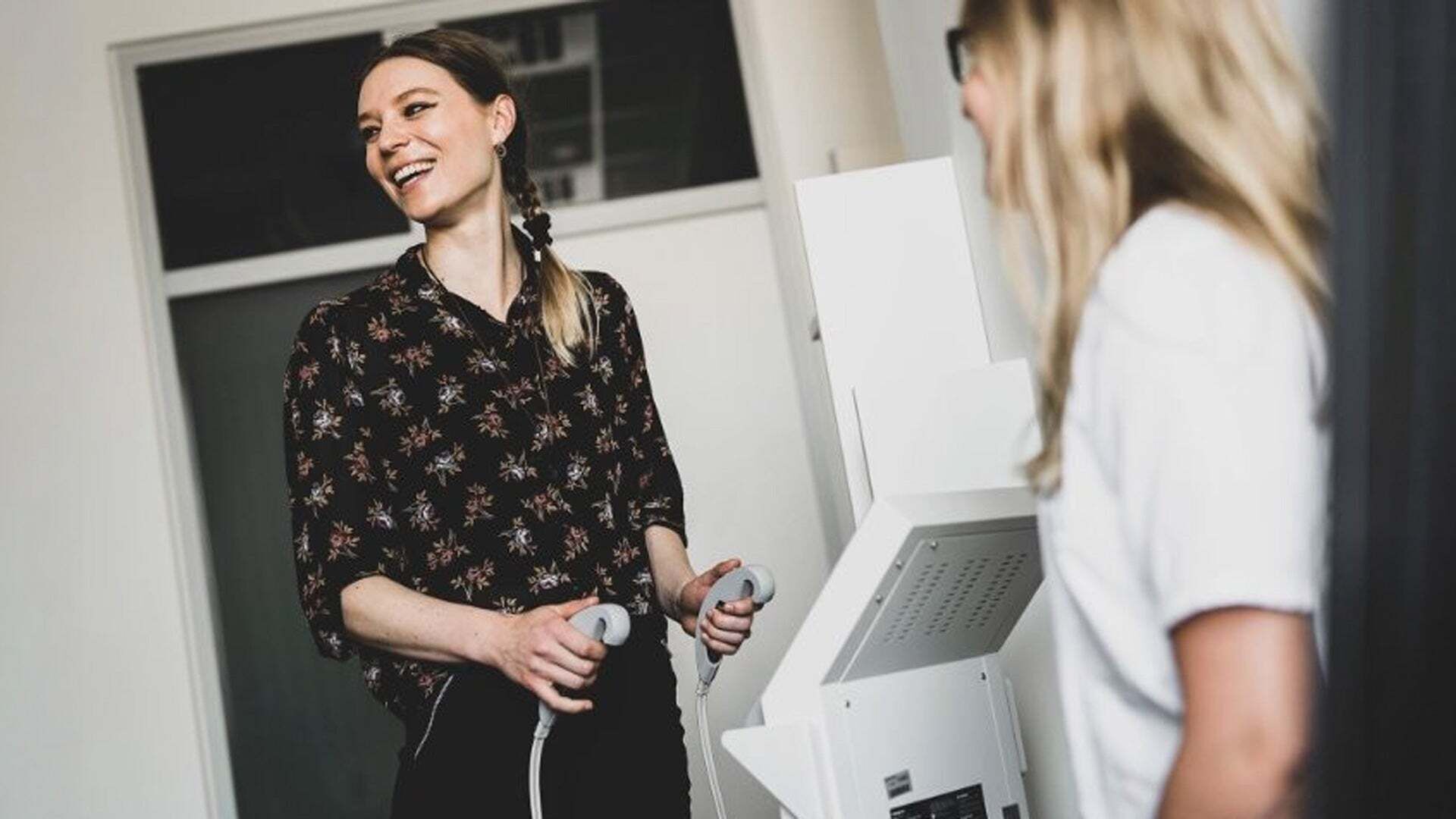 Zwei Personen stehen in einem Raum und bedienen gemeinsam ein medizinisches Gerät.