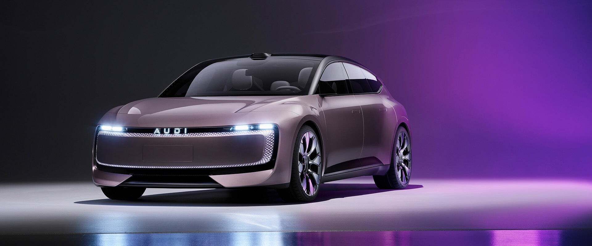 Das Audi-Konzeptfahrzeug mit futuristischem Design und durchgehender LED-Lichtsignatur steht in einer dunklen Studio-Umgebung mit violetter Beleuchtung, die sich auf dem Boden spiegelt.        