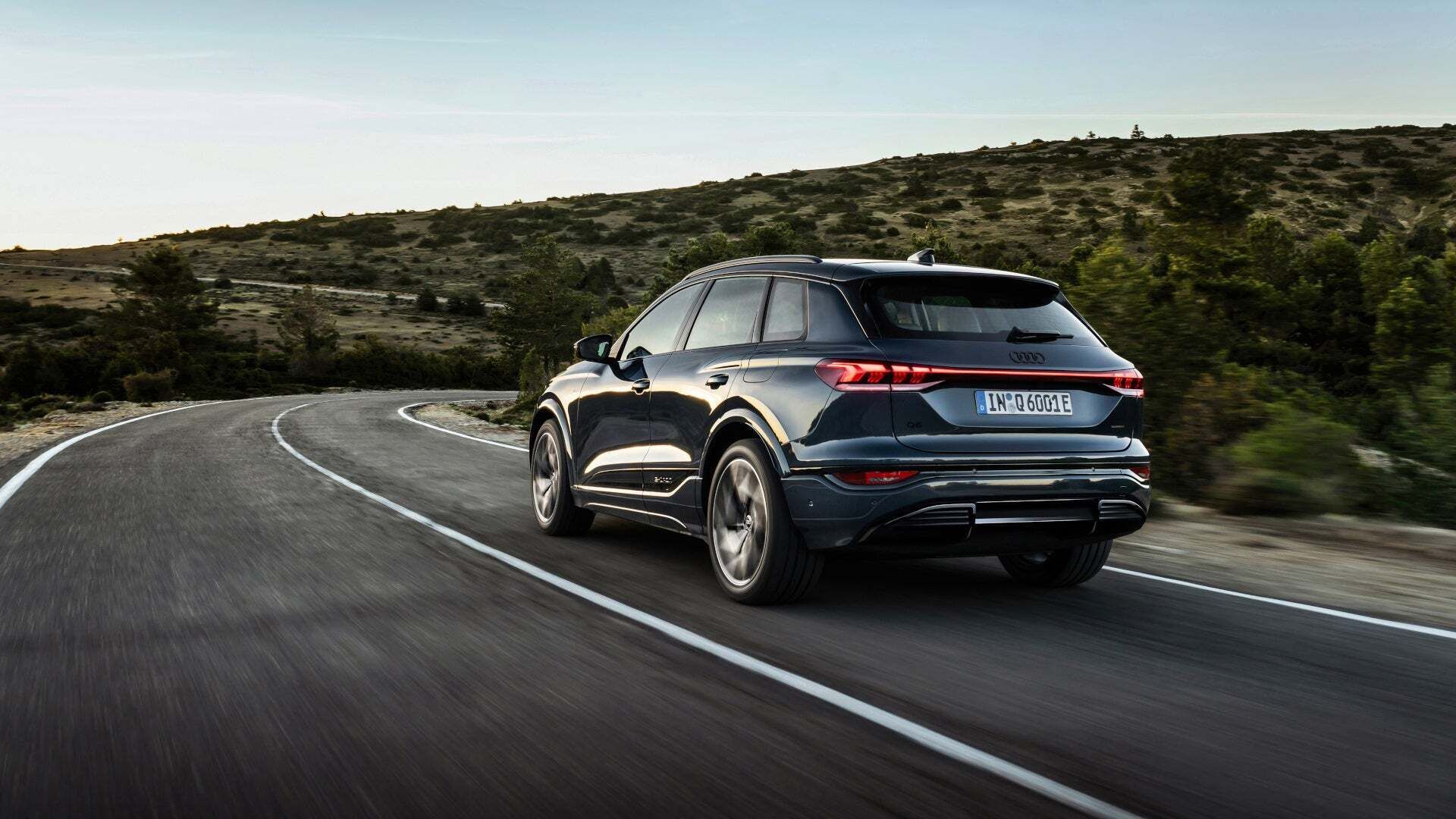 Ein schwarzer Audi Q6 e-tron quattro fährt über eine Landstraße