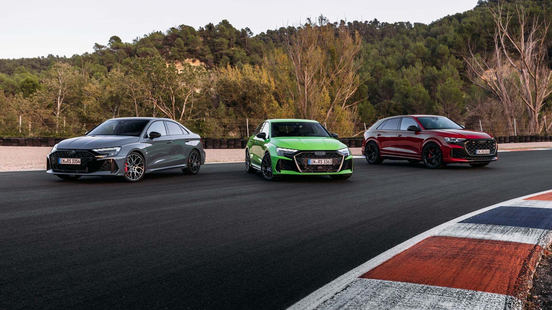 Three Audi RS models are lined up side by side on a race track.