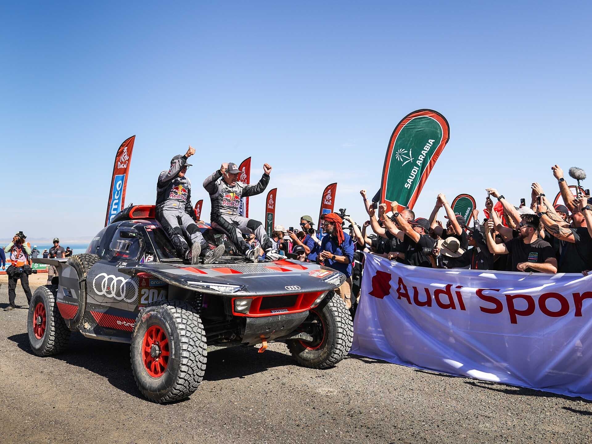 Das Foto zeigt, wie Carlos Sainz und Lucas Cruz ihren Sieg bei der Rallye Dakar 2024 feiern.