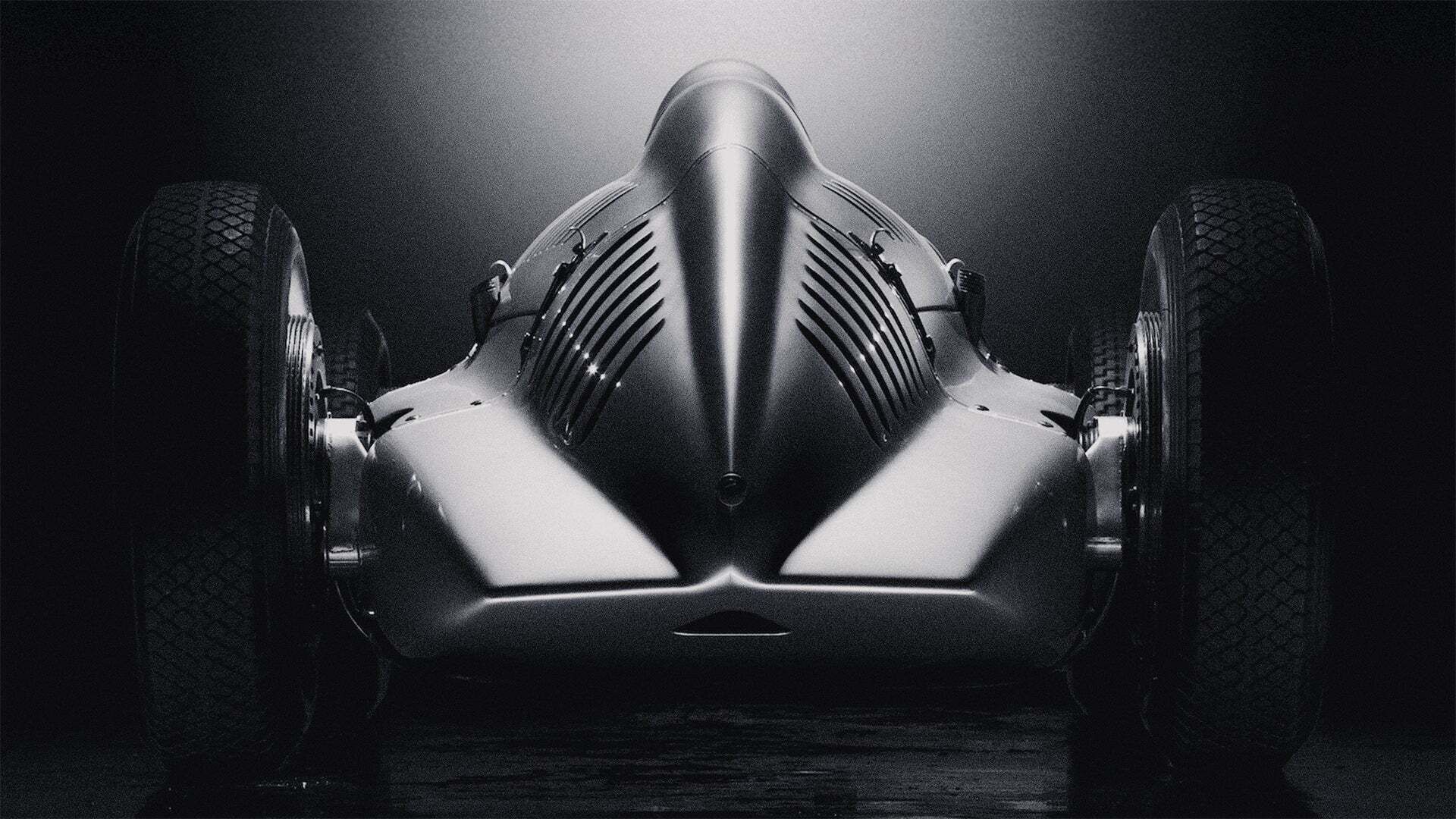 Rear view of a historic Audi racing car against a dark background.