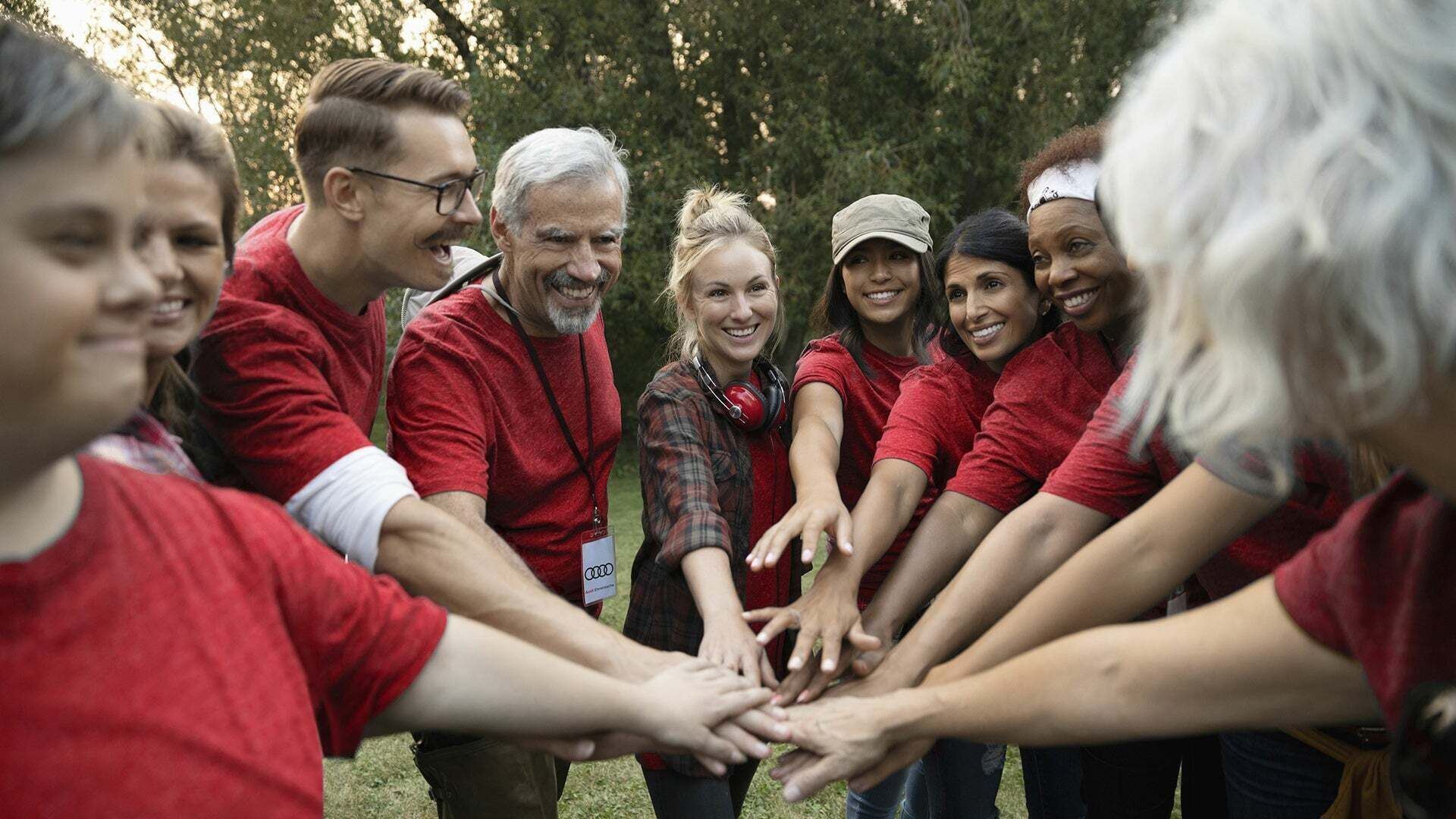 Eine Gruppe von Menschen in roten T-Shirts halten die Hände in der Mitte zusammen