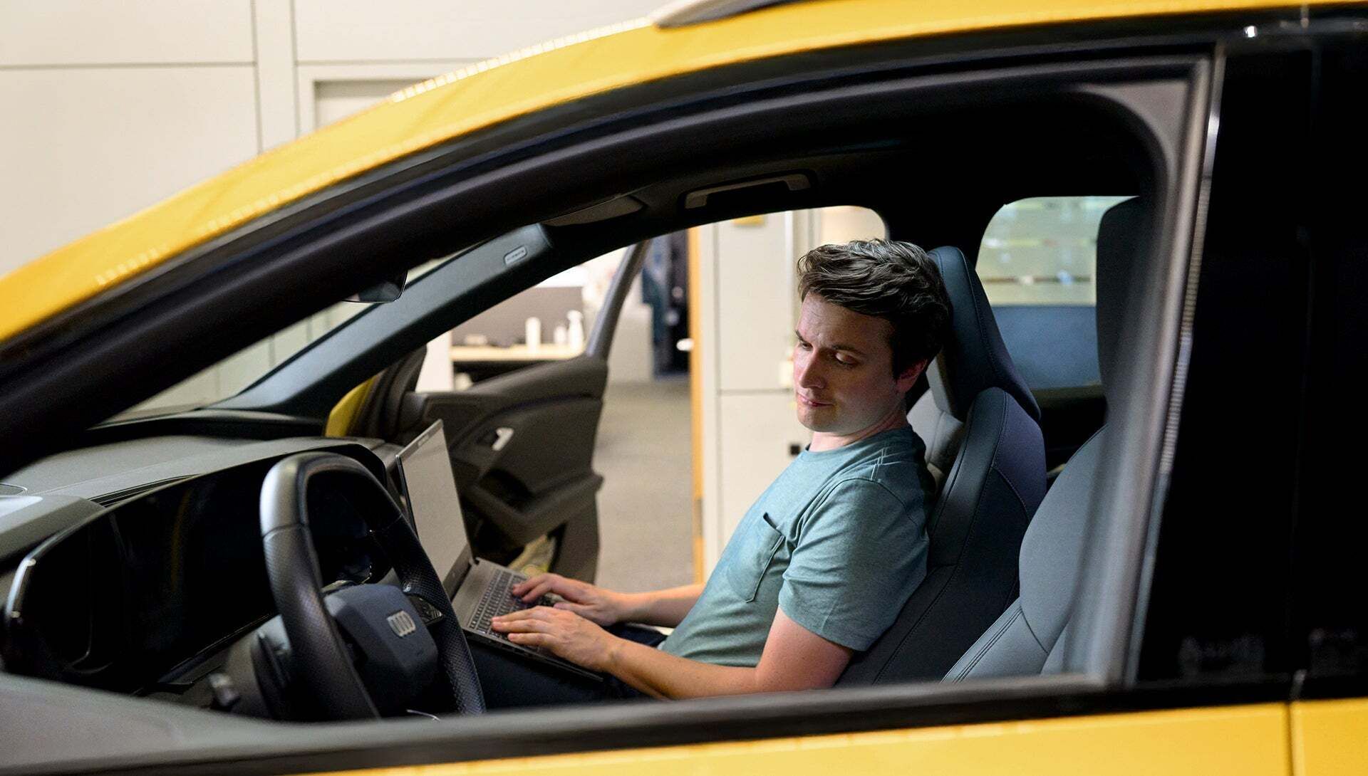 Jan Totz is sitting in the passenger seat of an Audi with a laptop on his lap, looking at the steering wheel