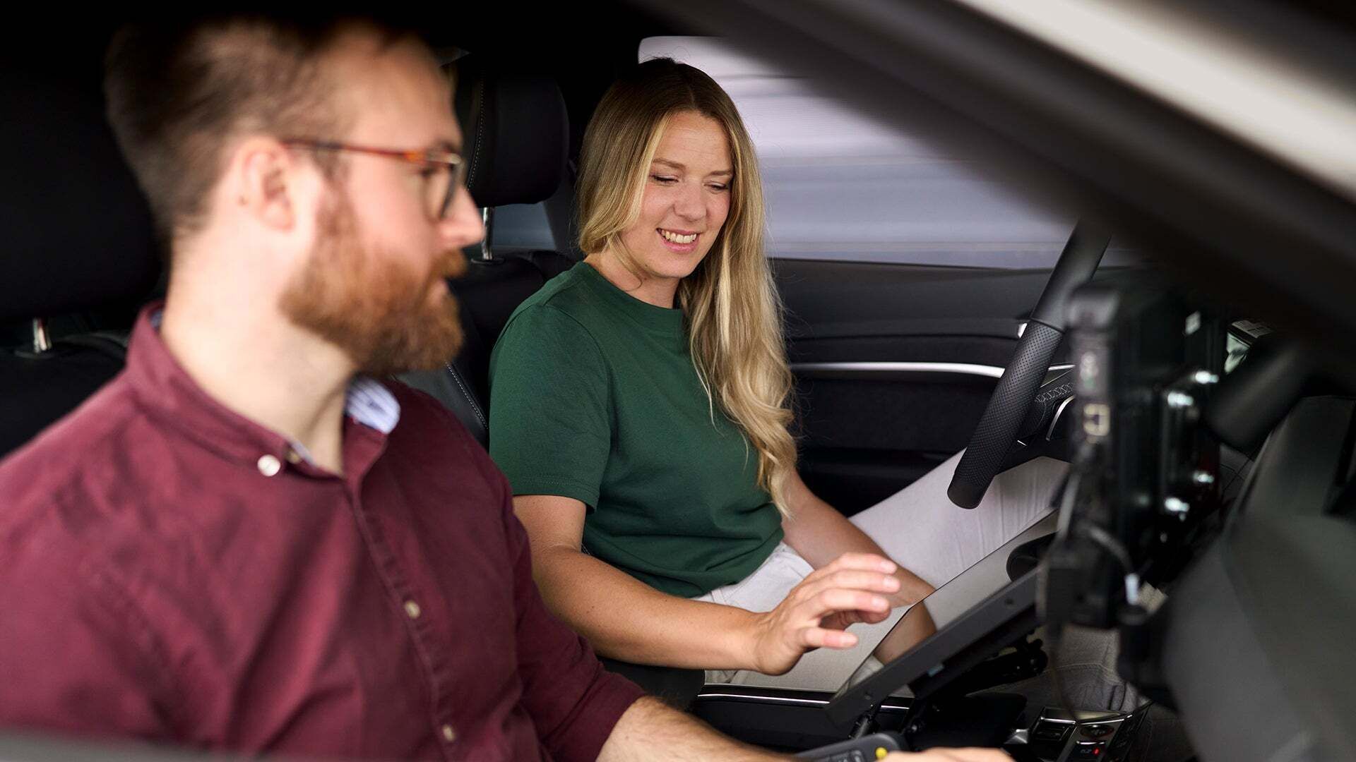 Lissi sitzt im Auto mit einem Kollegen und tippt auf einem IPad